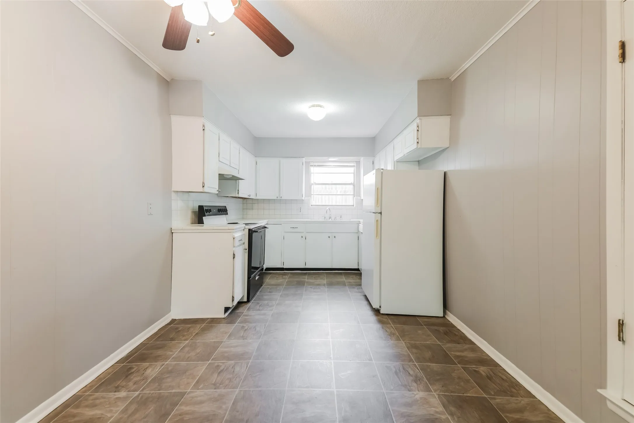 Kitchen featuring white cabinetry, a white tile backsplash, and a window above the sink