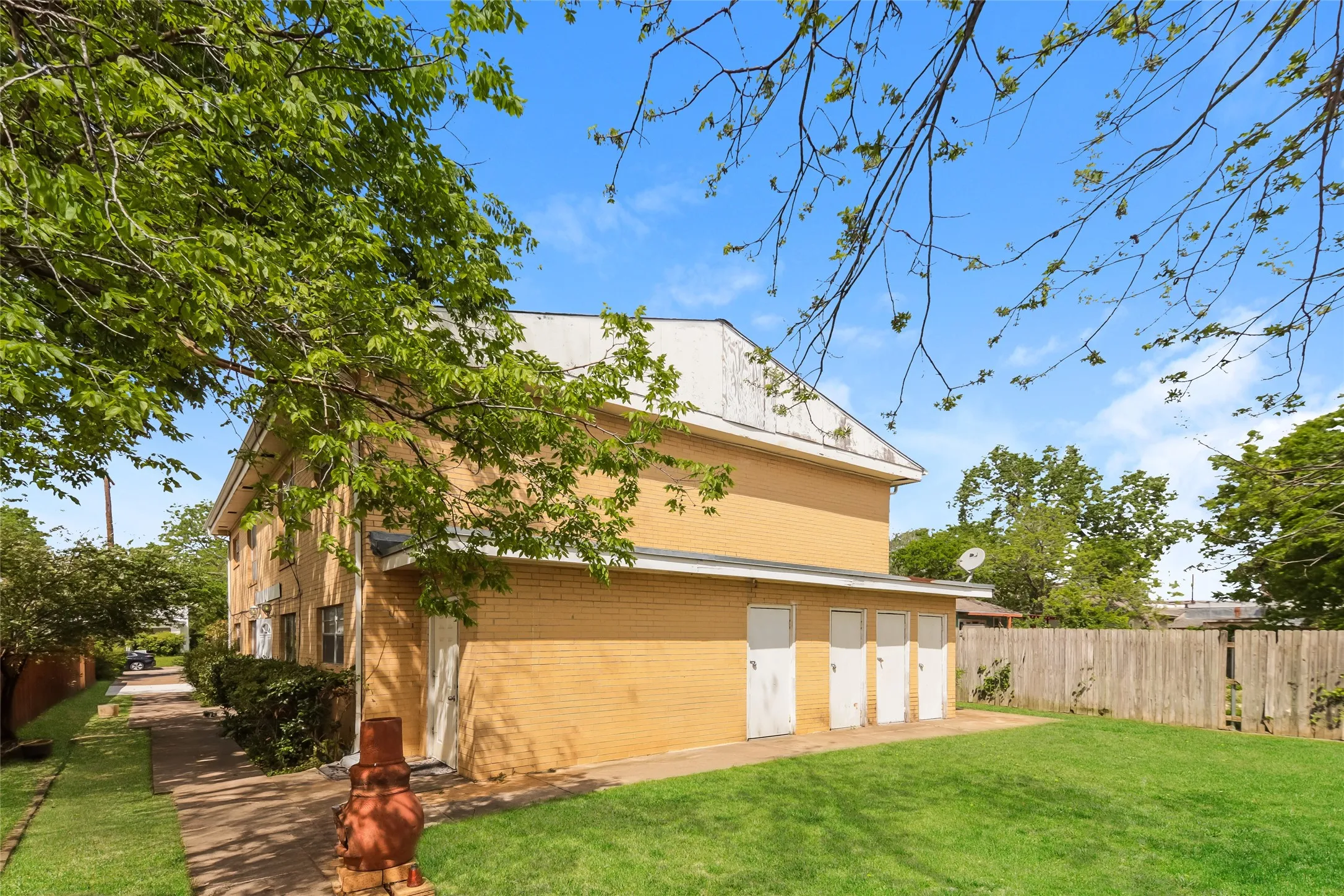 Expansive green lawn bordering a light brick exterior with multiple exterior storage doors