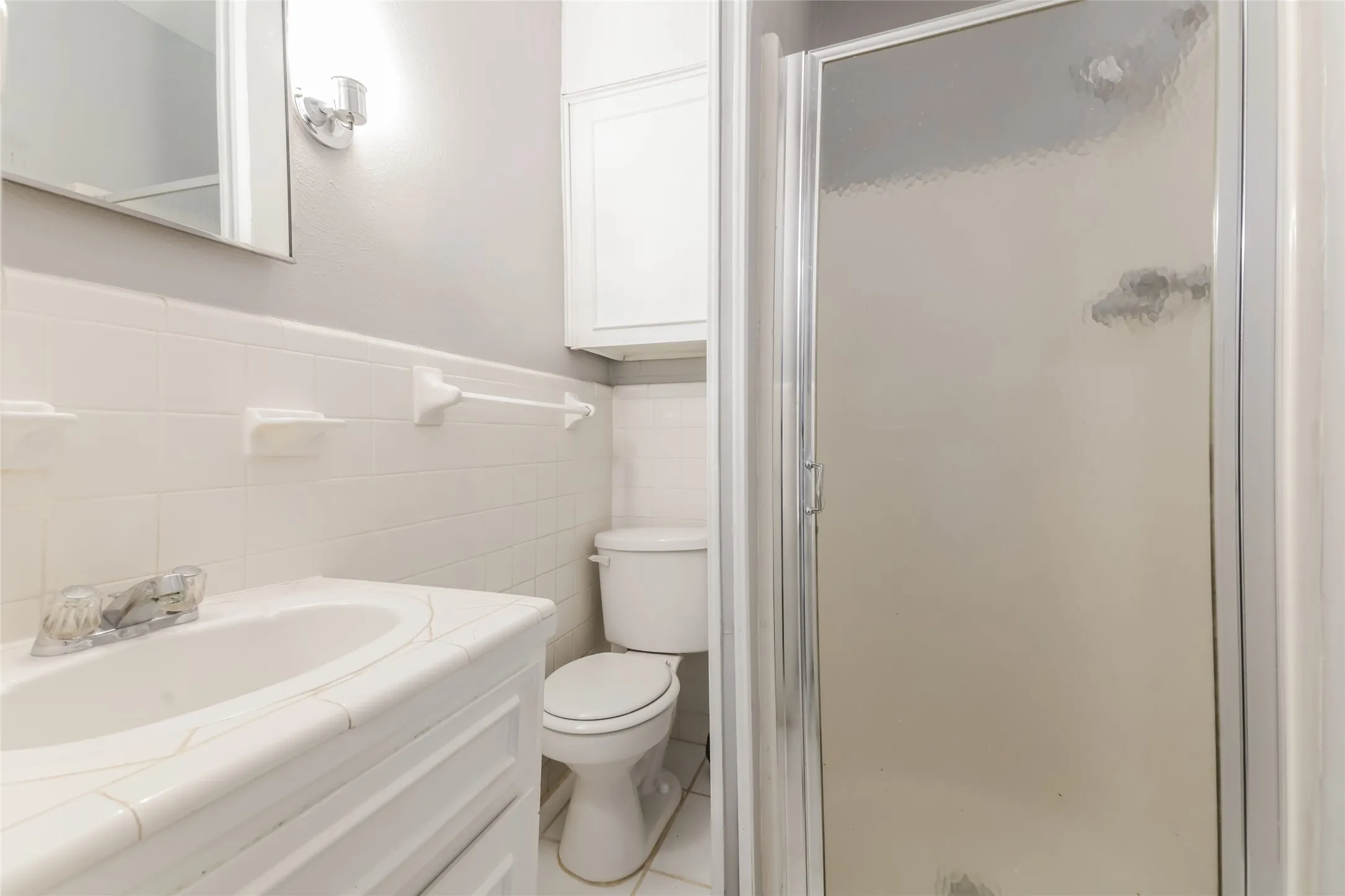 Bathroom featuring a white vanity with integrated sink, chrome faucet, and mirrored medicine cabinet