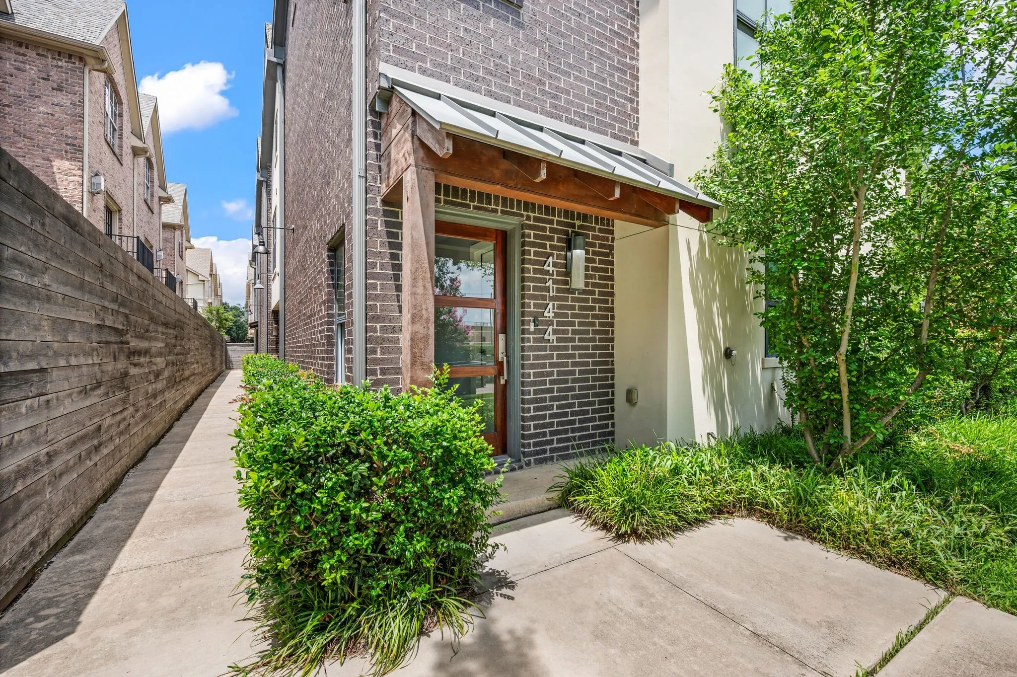 Brick facade with a contemporary wood door and an architectural metal awning