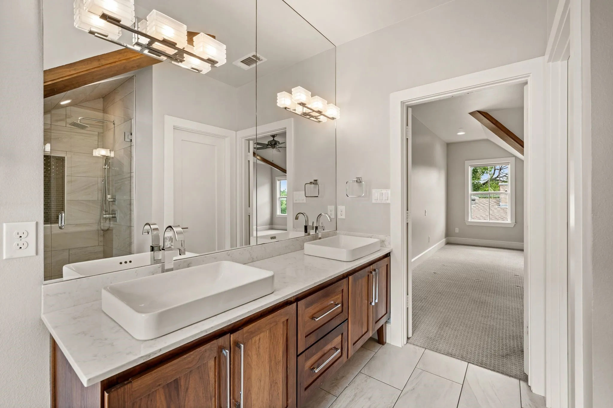 Contemporary bathroom featuring a double vanity with vessel sinks, wood cabinetry, and a light-toned countertop