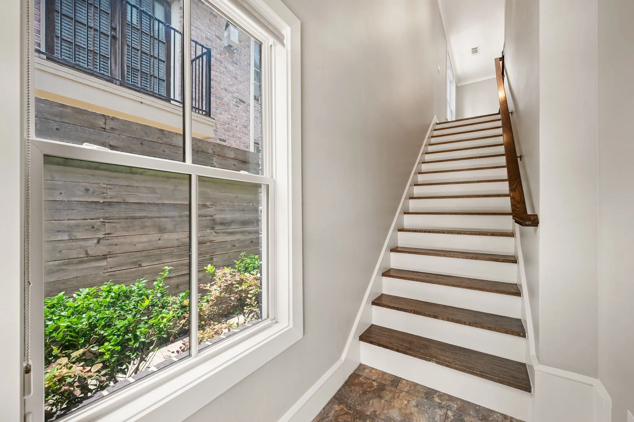 Staircase featuring wood-finish treads and white risers with a coordinating wood handrail