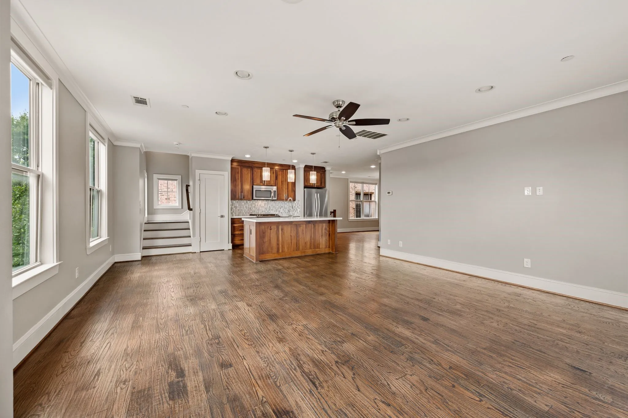 Open-concept living space featuring wood-finish flooring, recessed lighting, and a ceiling fan