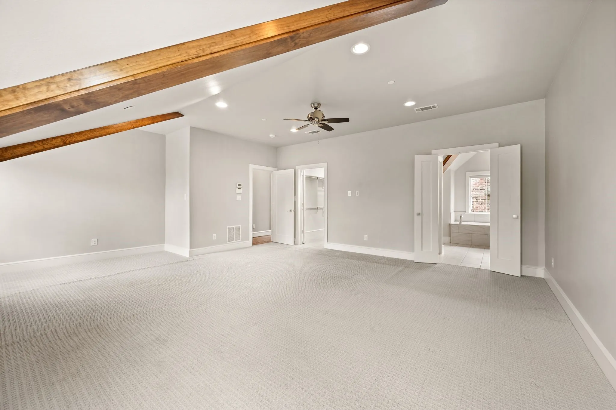 Expansive walk-in closet featuring white built-in shelving, chrome hanging rods, a textured carpet floor, and overhead fluorescent lighting