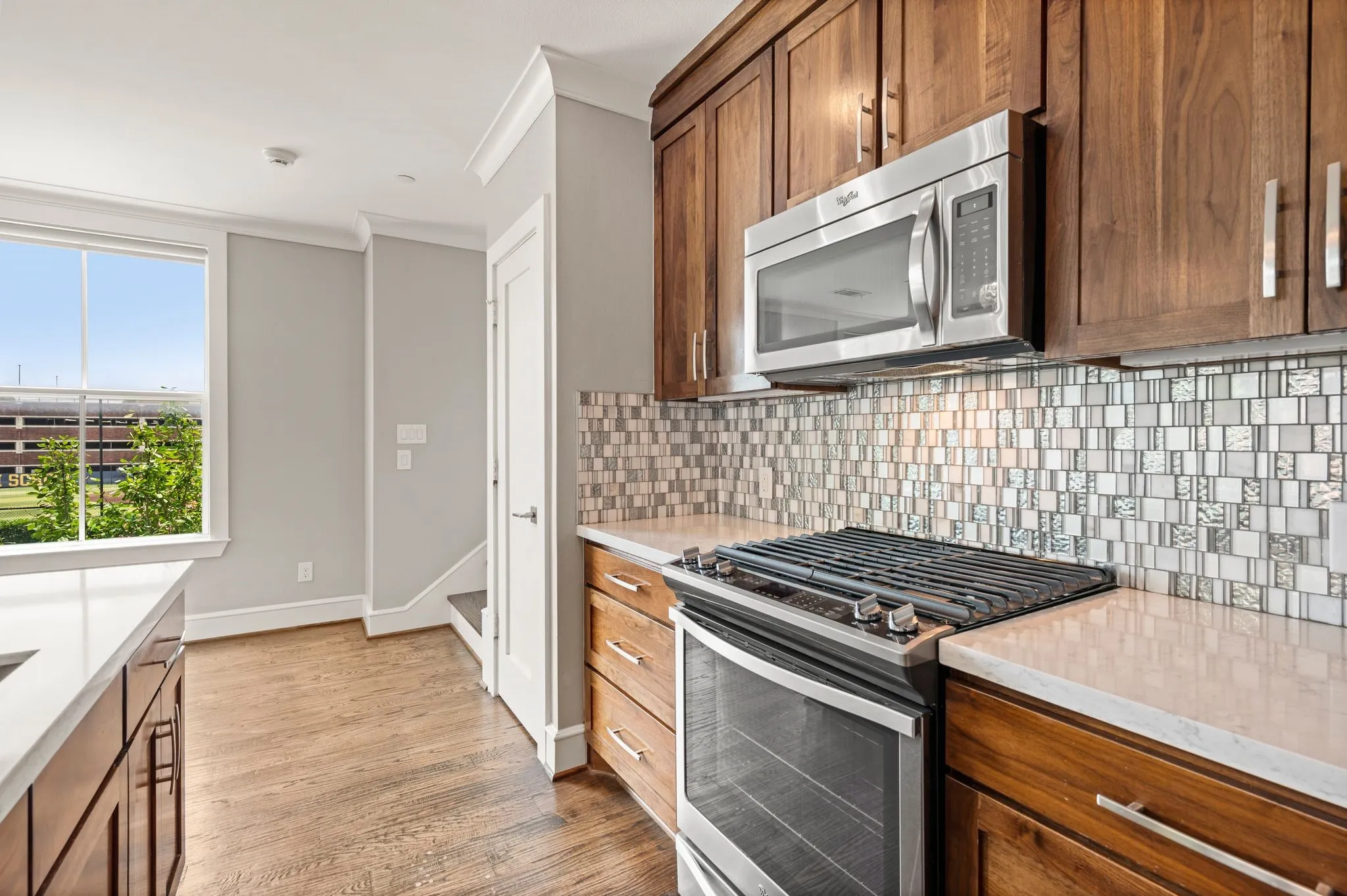 Kitchen featuring wood-finish cabinetry, stainless steel appliances, a mosaic tile backsplash, and light-toned countertops
