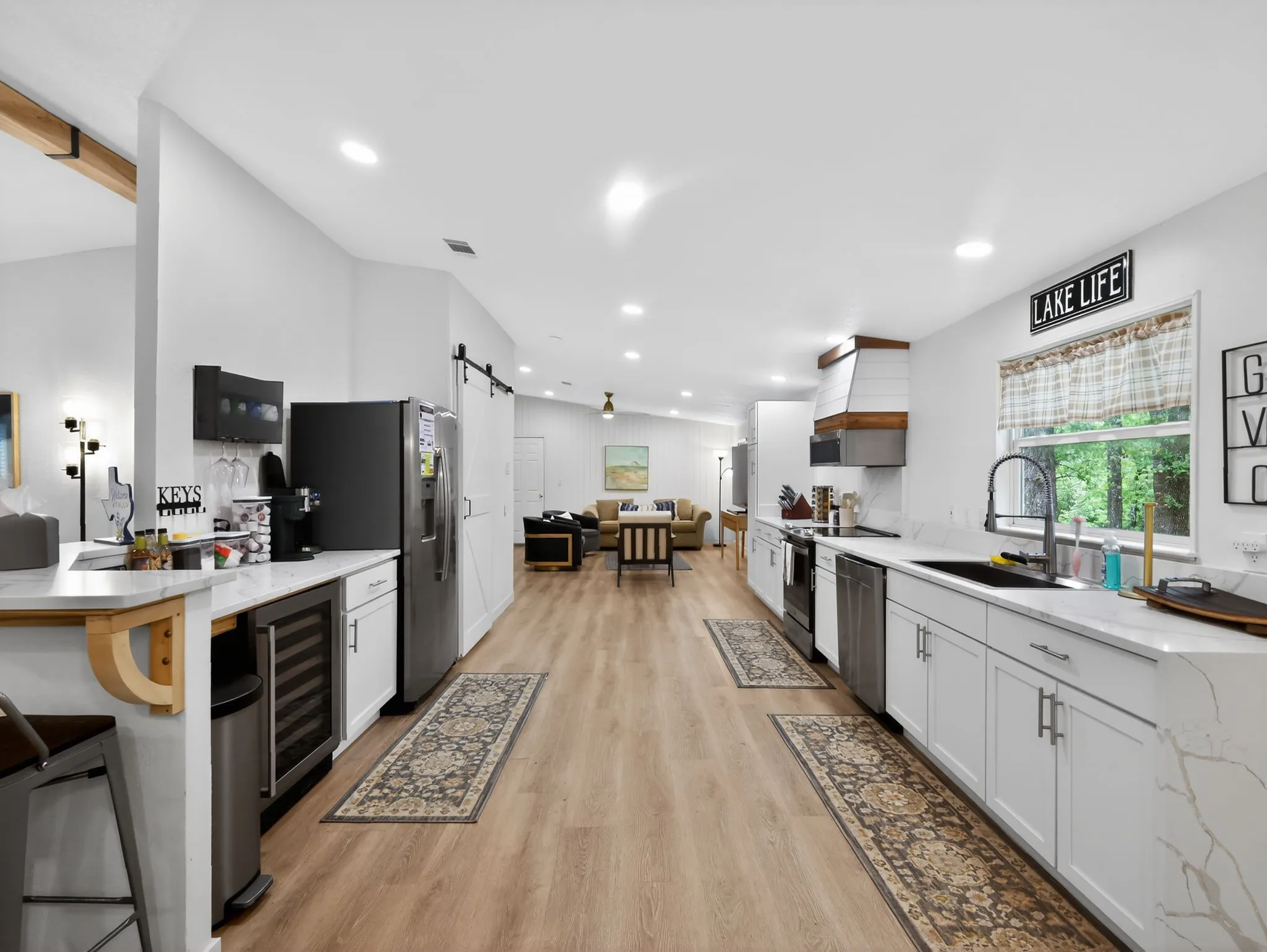Modern kitchen featuring light wood-finish flooring, white cabinetry, and a waterfall-edge countertop