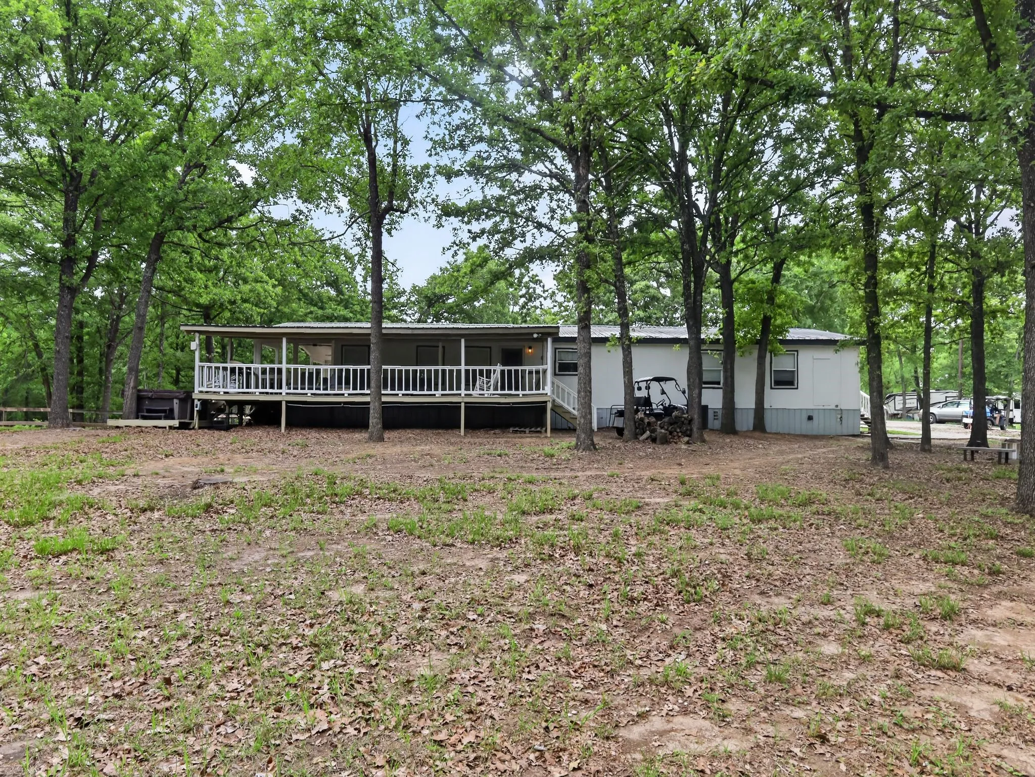 Property exterior featuring a full-length covered porch with white railing, set among mature trees