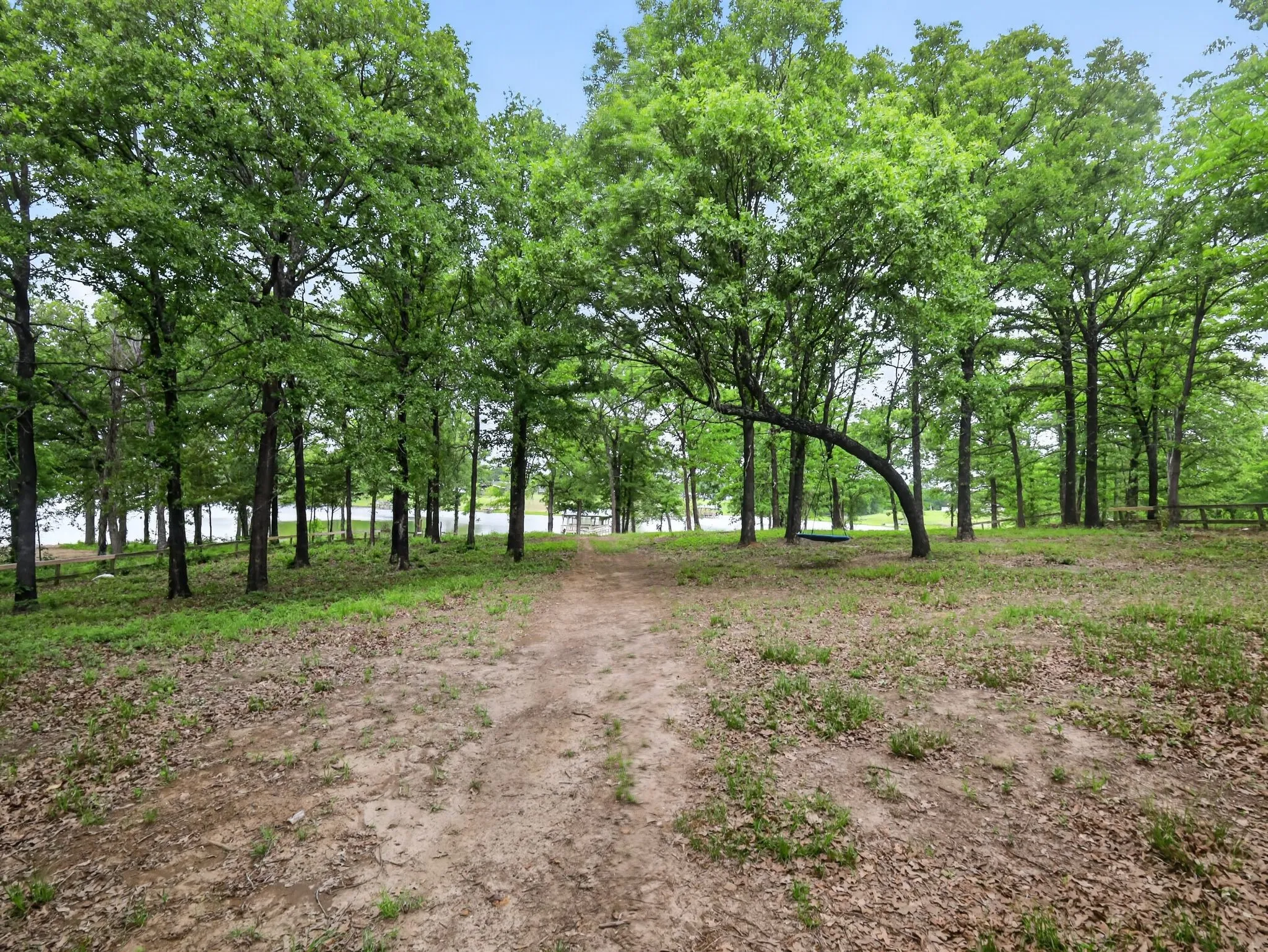 Wooded property featuring a natural pathway, mature deciduous trees, and distant water frontage