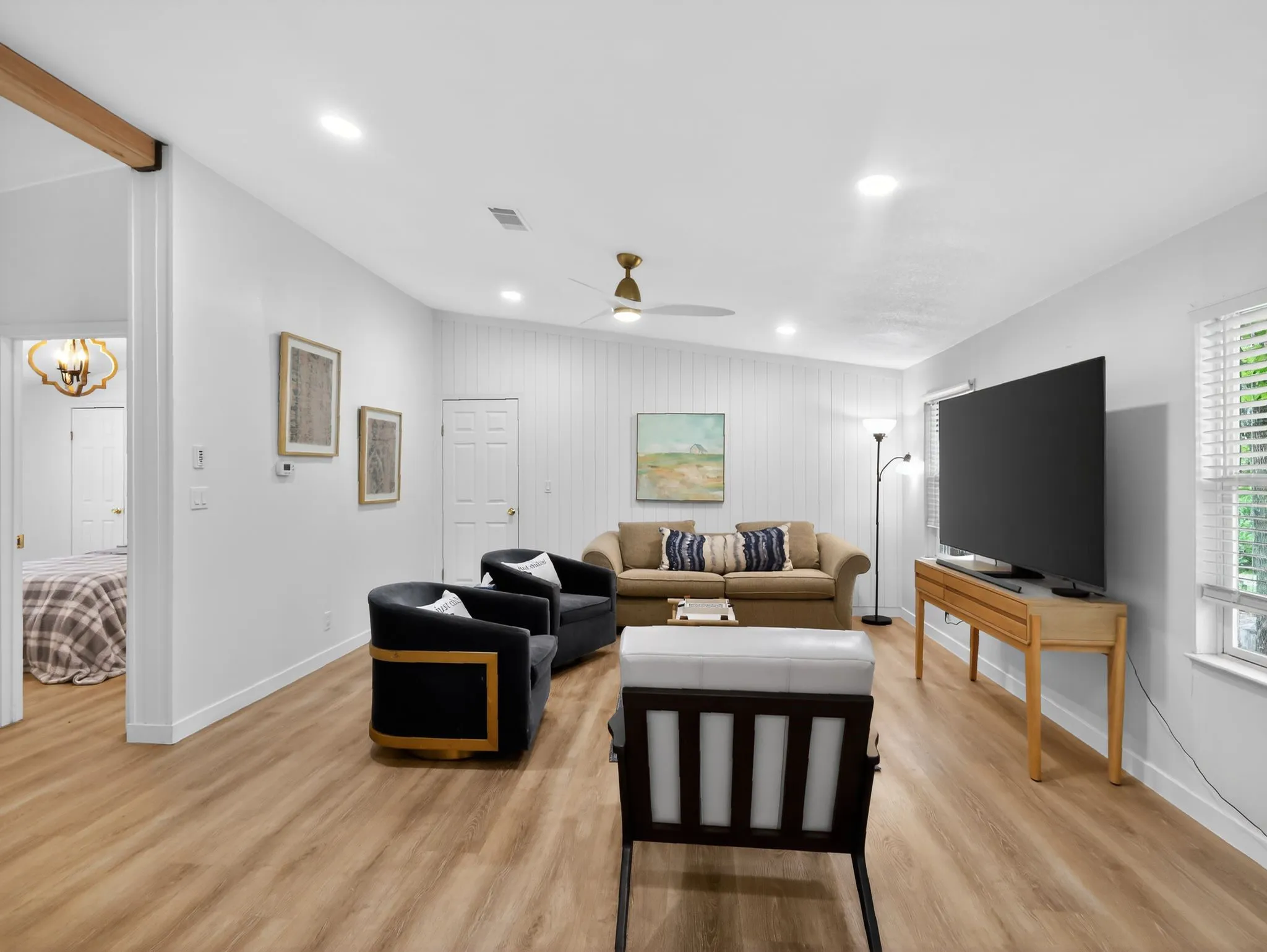 Bright living area featuring recessed lighting, wood-finish flooring, and white paneled accent walls