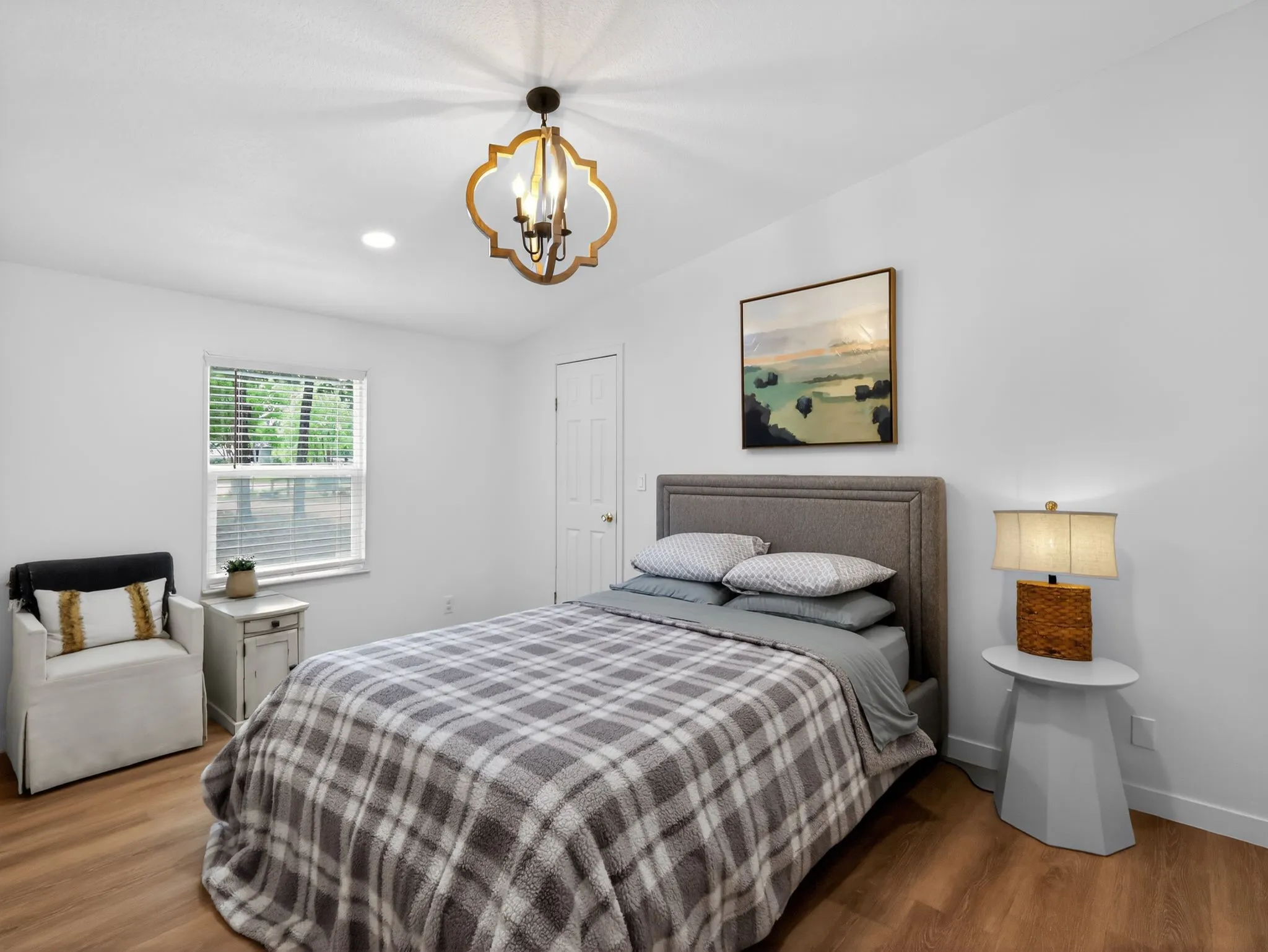 Recessed lighting and a decorative chandelier illuminate this room featuring wood-finish flooring