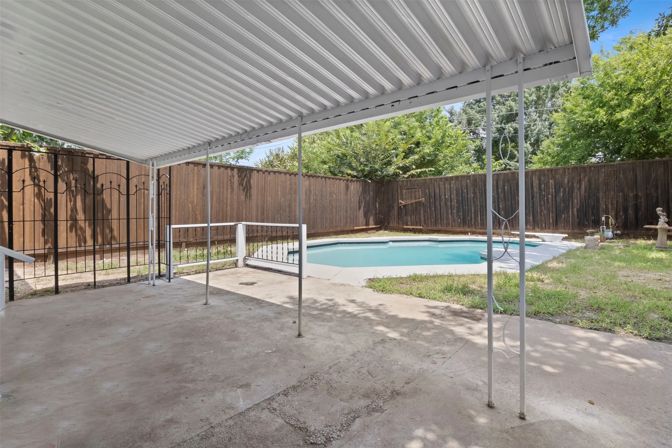 Covered patio space featuring a concrete slab, metal support columns, and a corrugated metal roof