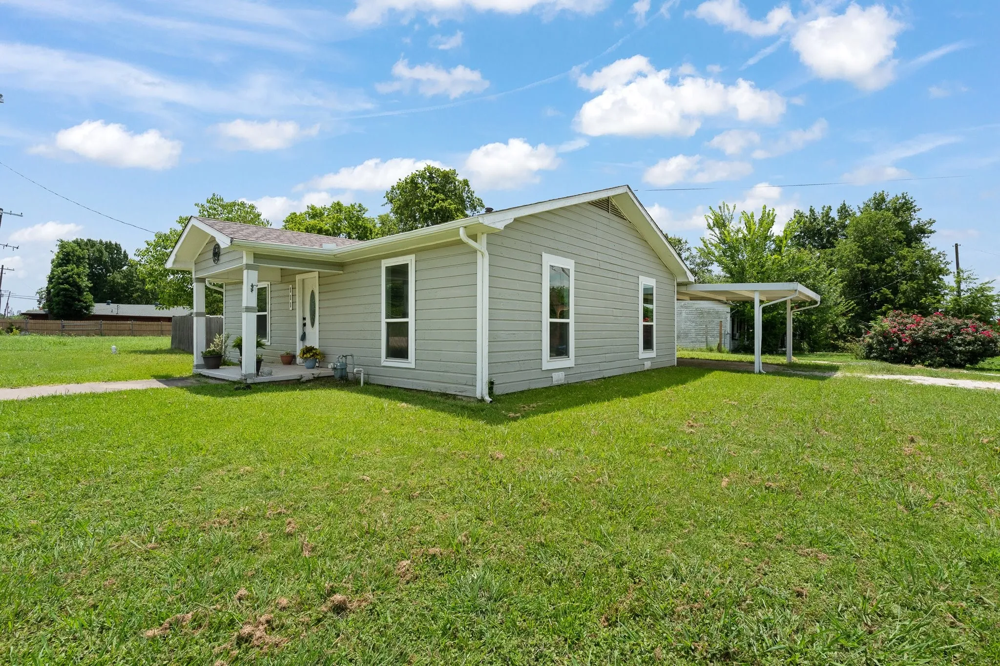 Single-story residence featuring light gray siding, white trim, and a covered front porch with white pillars