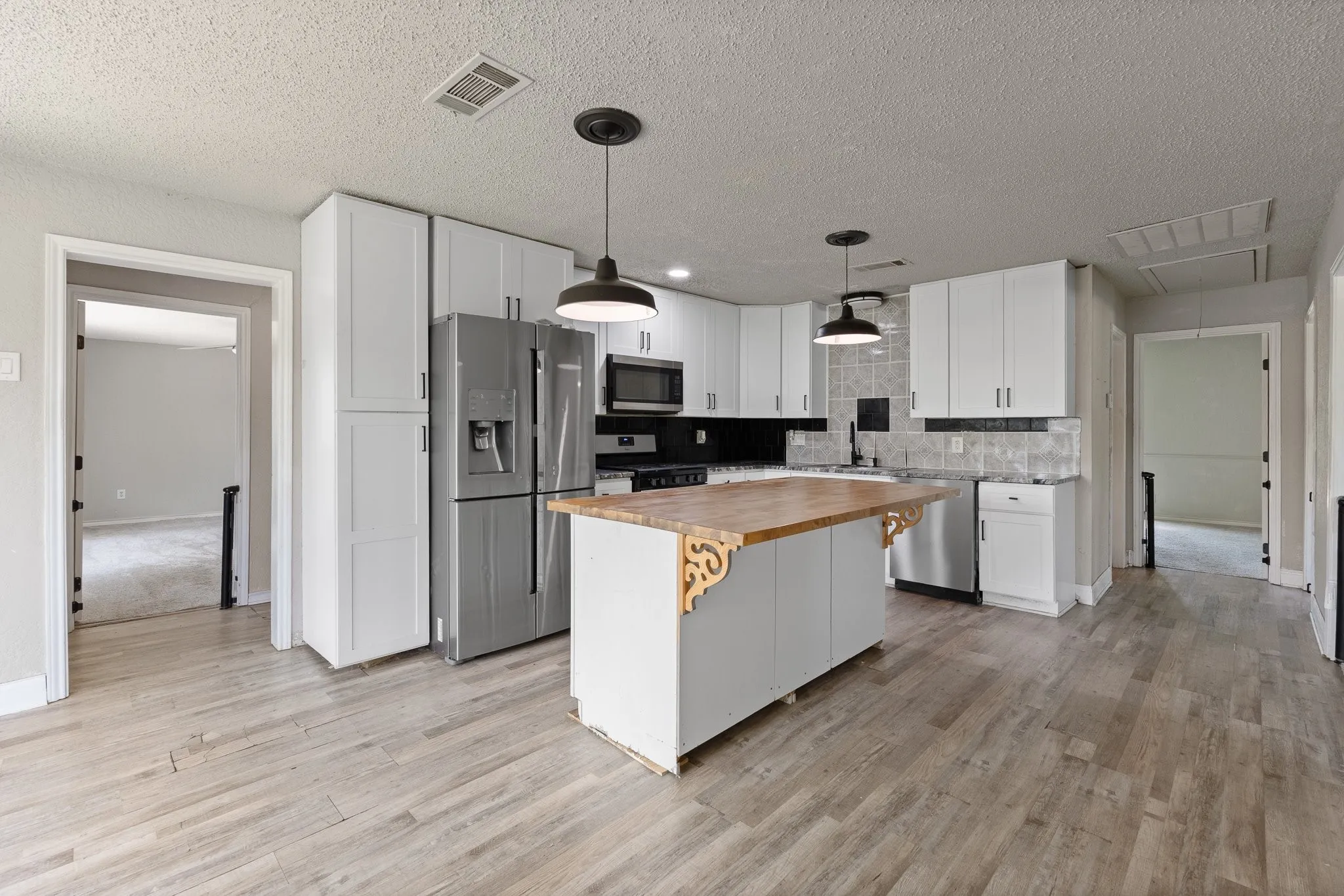 Kitchen featuring wood-finish flooring, white cabinetry, and stainless steel appliances