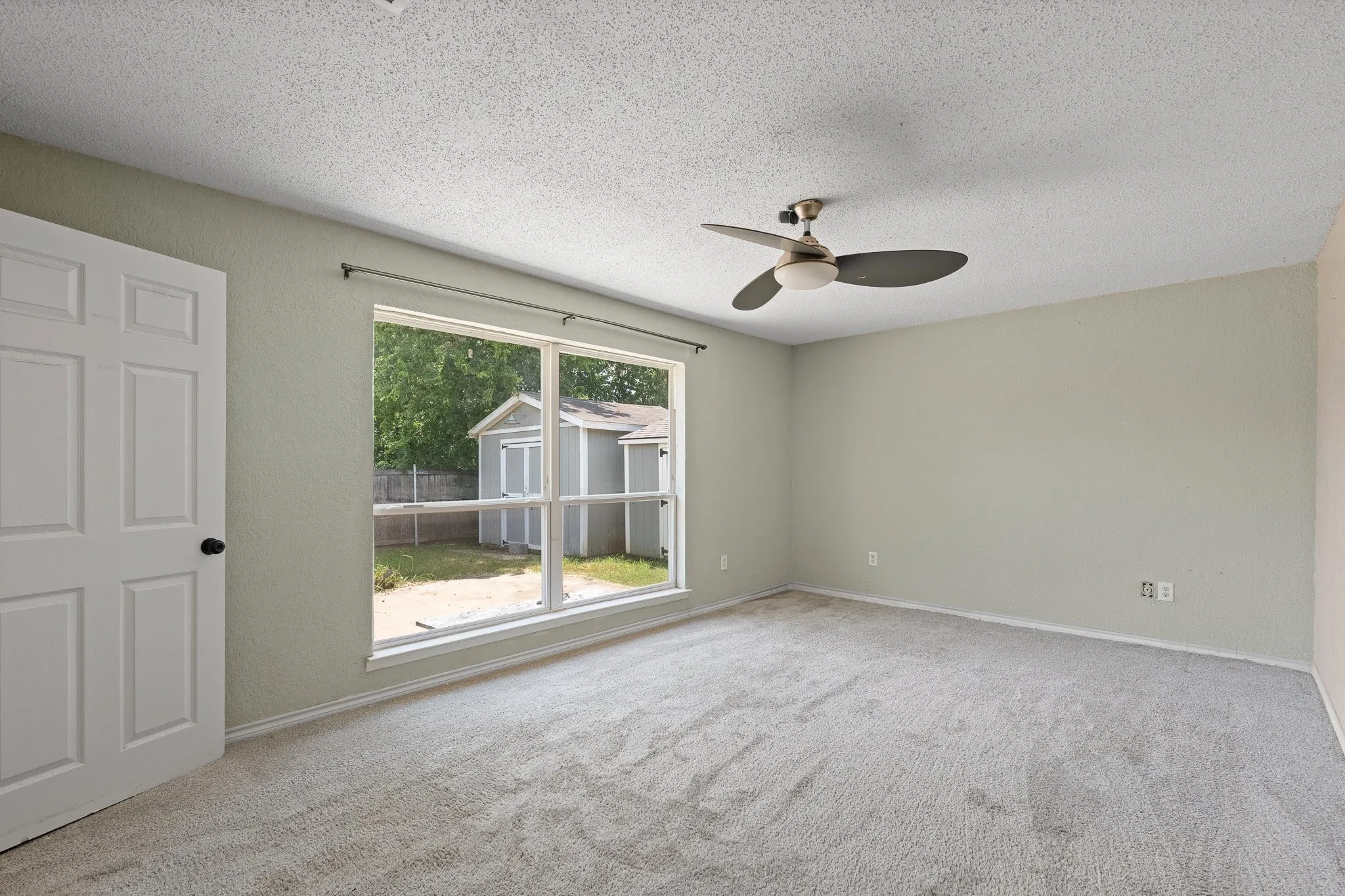 Spacious room featuring light-colored walls, textured ceiling, and neutral carpet flooring