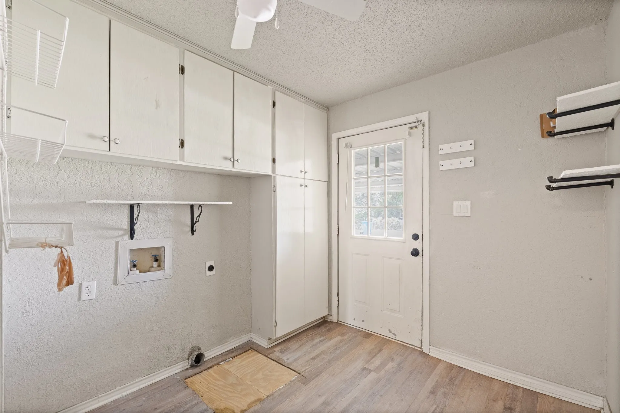 Dedicated utility room featuring abundant built-in cabinetry, wood-finish flooring, a ceiling fan, a rear exterior door, and laundry hookups