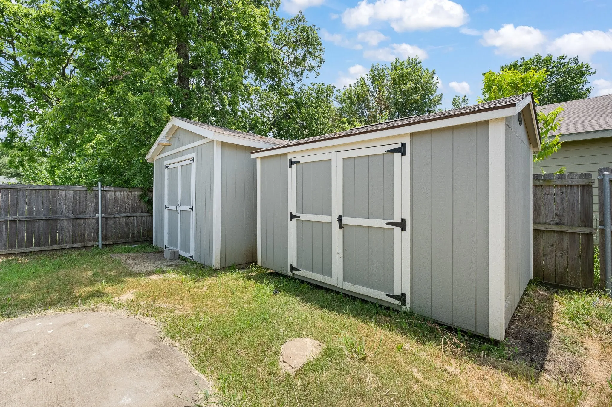 Two detached sheds with light gray siding and white trim