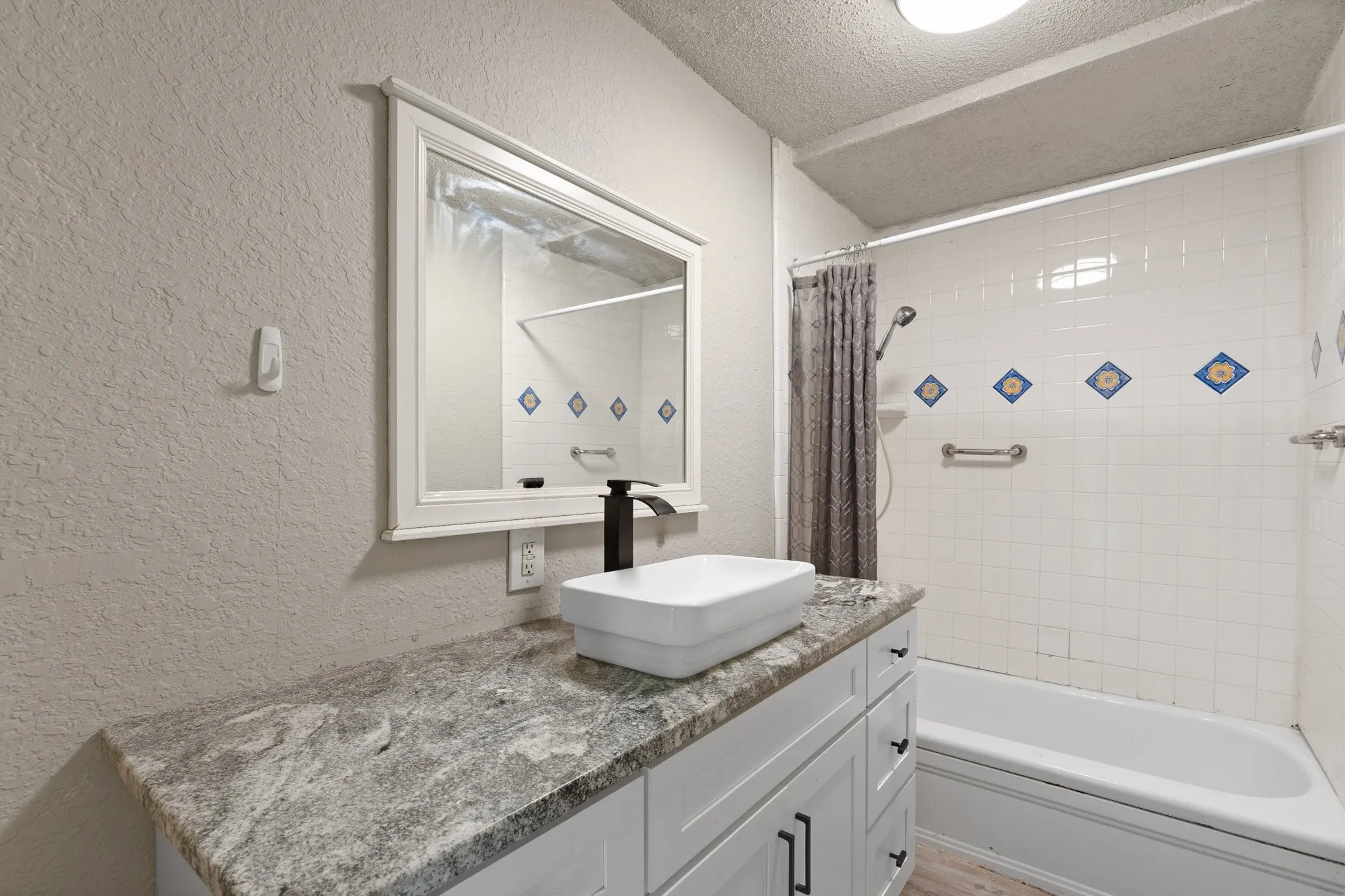 Bathroom featuring a spacious vanity with a stone countertop, a modern vessel sink, and a black faucet