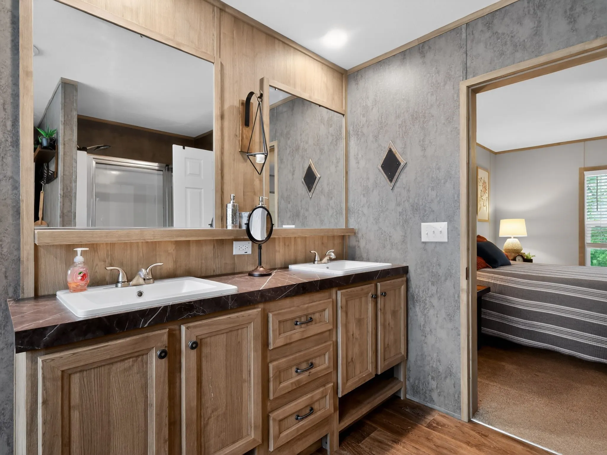 Dual vanity with integrated sinks, wood-finish cabinetry, and a patterned countertop