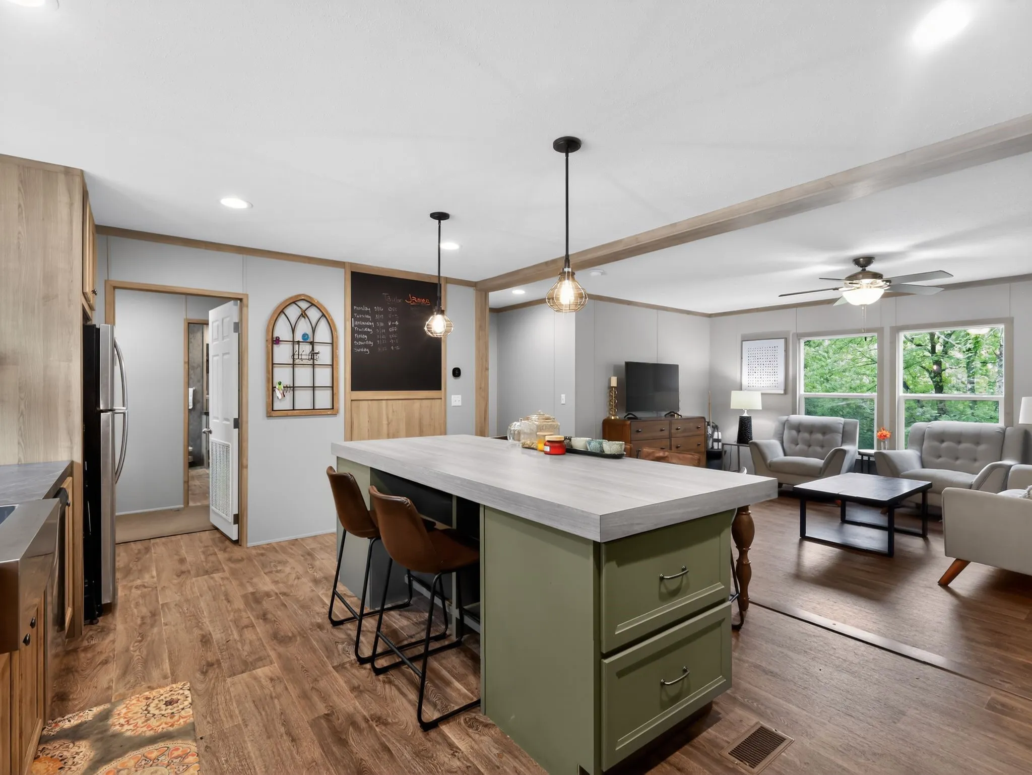 Open-concept kitchen and living area featuring wood-finish flooring, a kitchen island with seating, pendant lighting, and a ceiling fan