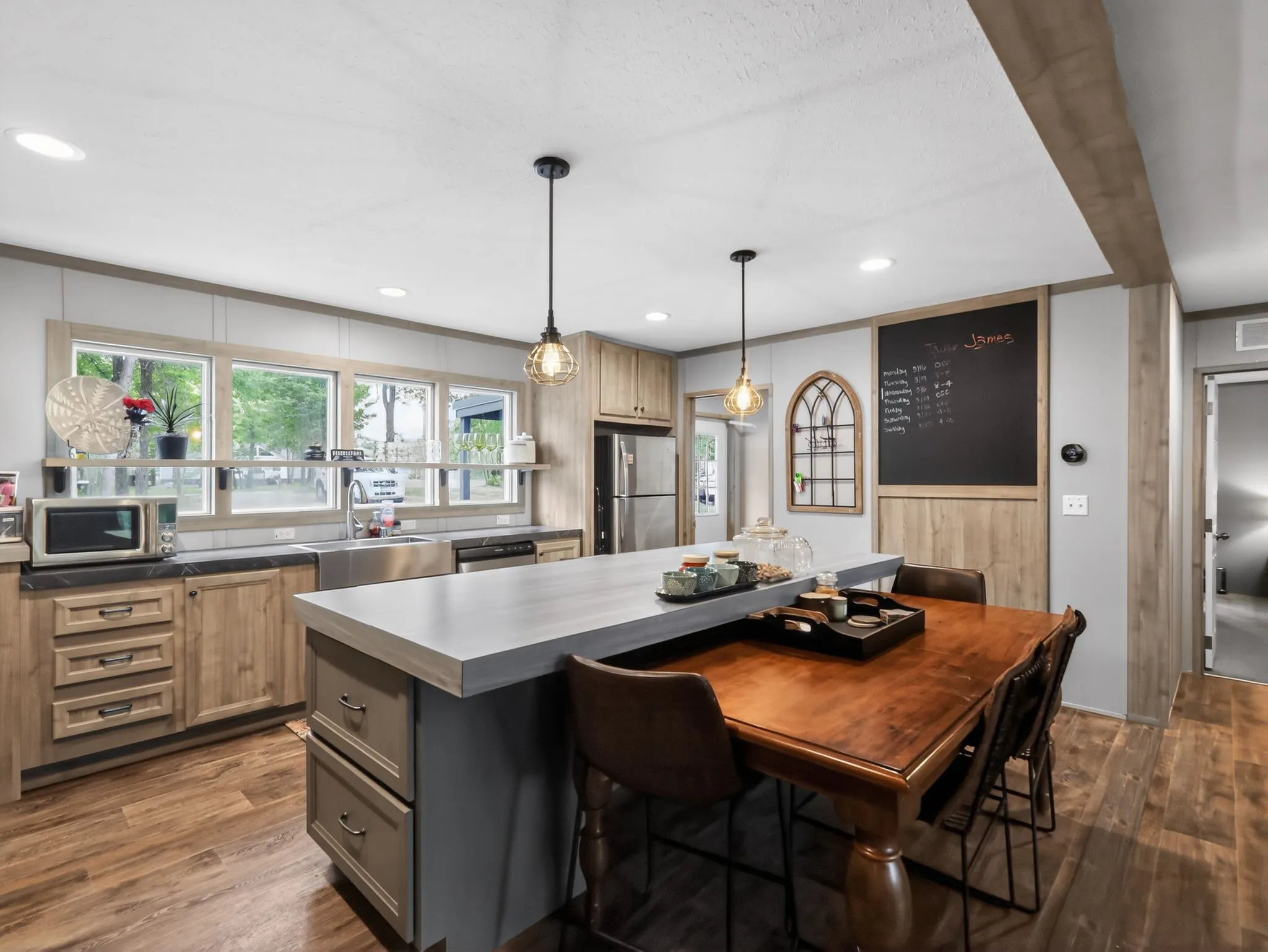 Open-concept kitchen with wood-finish flooring, recessed lighting, and pendant fixtures