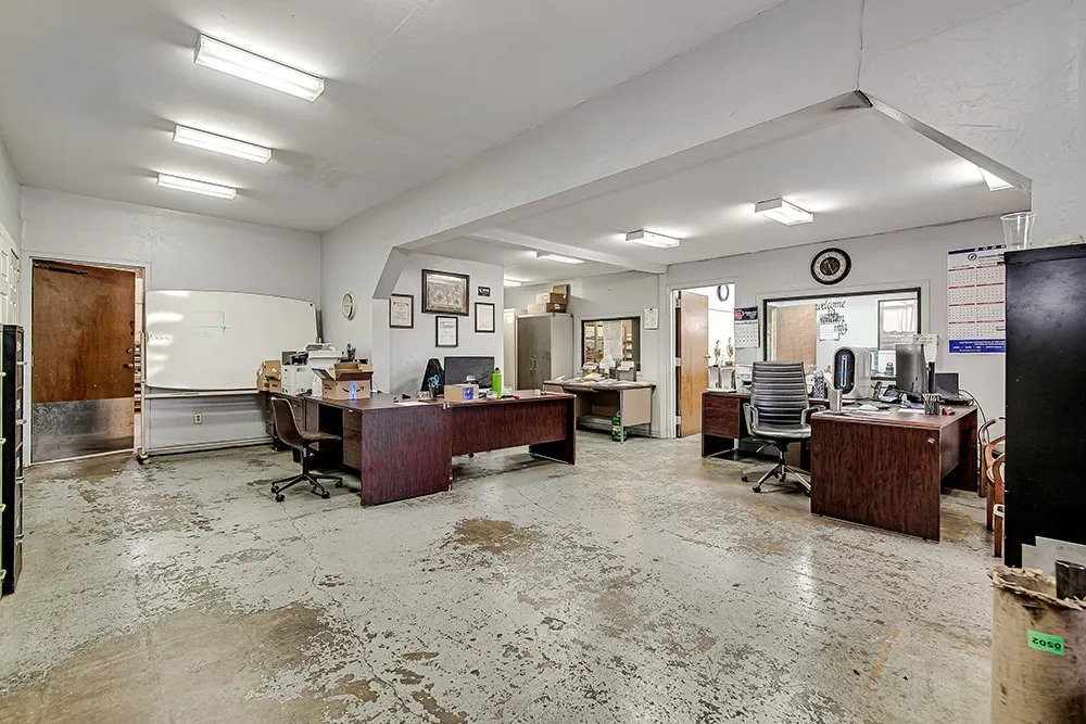 Open-plan office space featuring concrete flooring and fluorescent lighting
