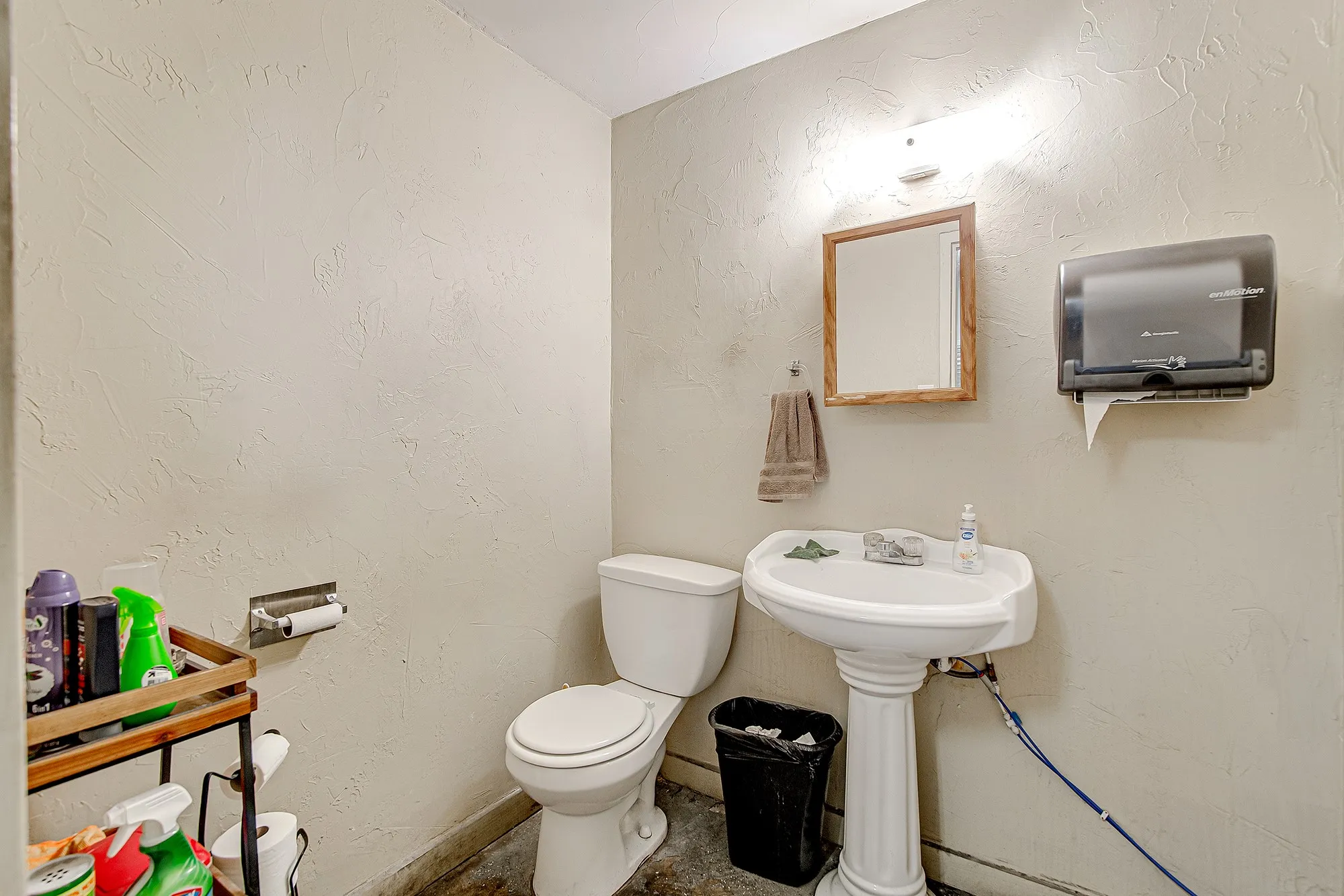 Powder room featuring a pedestal sink, wall-mounted mirror with wood-finish frame, and textured wall finish