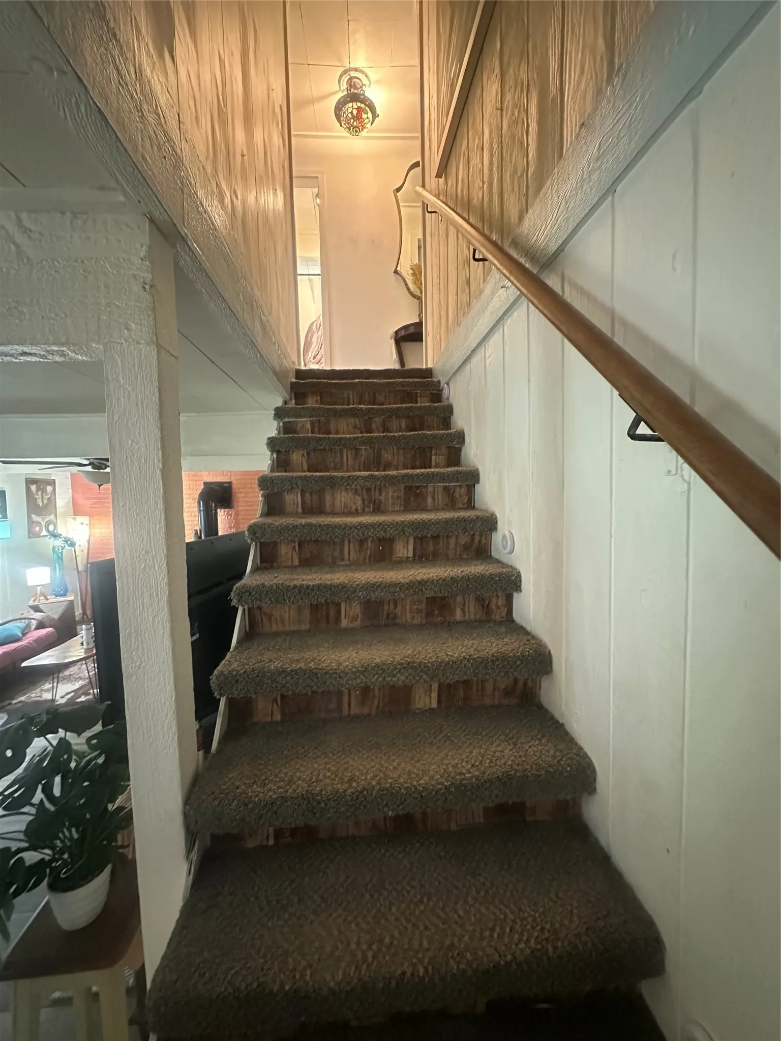 Carpeted staircase featuring wood-panel risers and a wood handrail