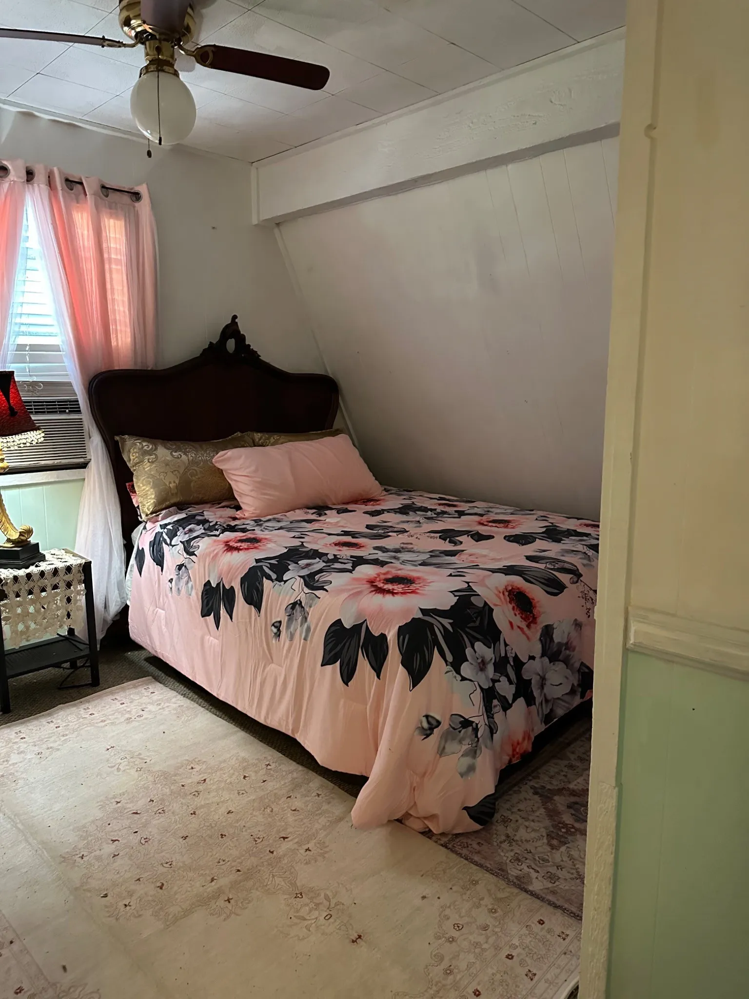 Sloped wall room featuring a ceiling fan with integrated lighting, wood-finish headboard, window with horizontal blinds, and a patterned area rug
