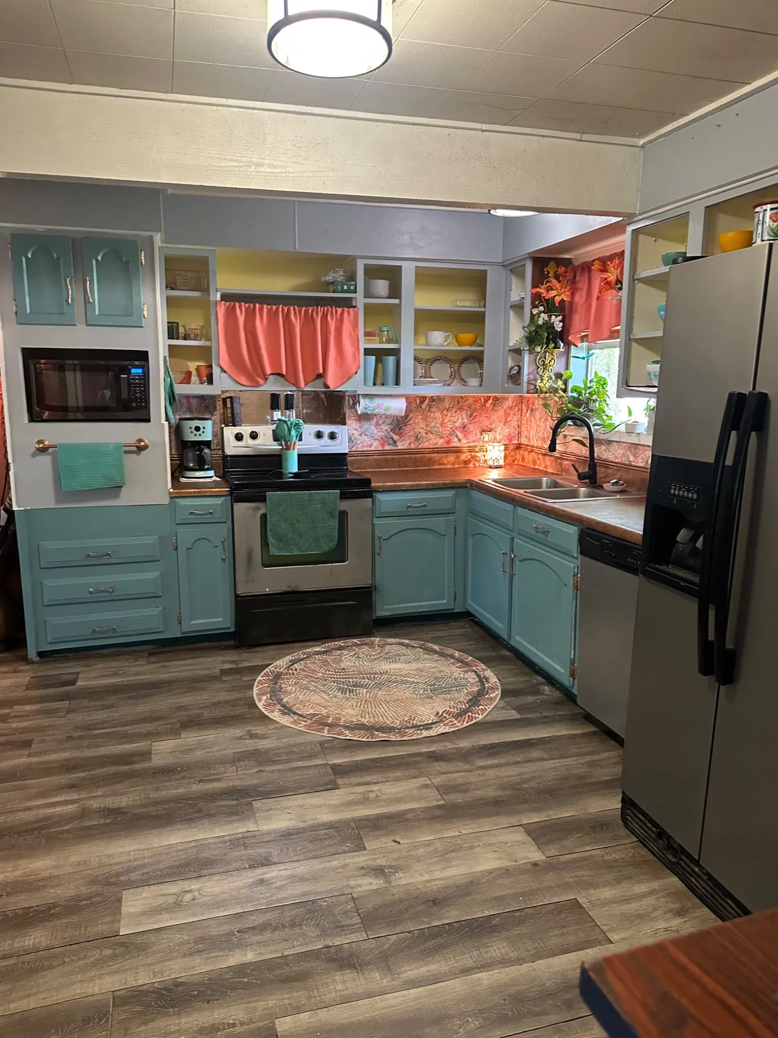 Kitchen featuring wood-finish flooring, light blue cabinetry, built-in microwave, and a stainless steel refrigerator