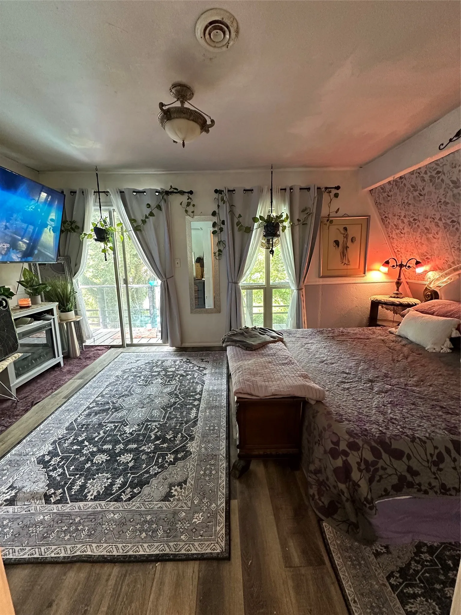 Spacious room featuring wood-finish flooring, a decorative area rug, and a ceiling-mounted light fixture