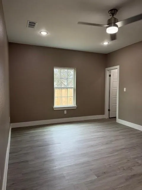 Spacious room featuring wood-finish flooring, recessed lighting, and a contemporary ceiling fan