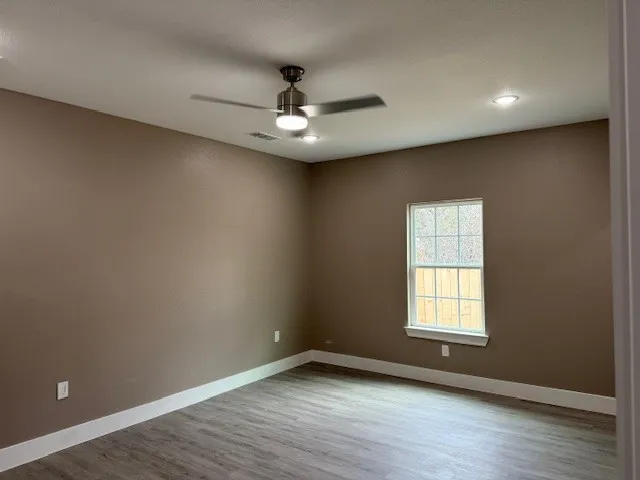 Room featuring wood-finish flooring, a double-hung window, white baseboards, a ceiling fan with integrated lighting, and recessed ceiling lights