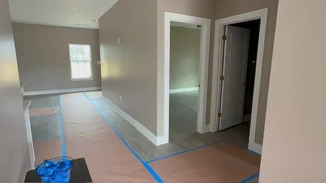 Interior space featuring light wood-finish flooring, neutral-toned walls, white trim, and a window with natural light