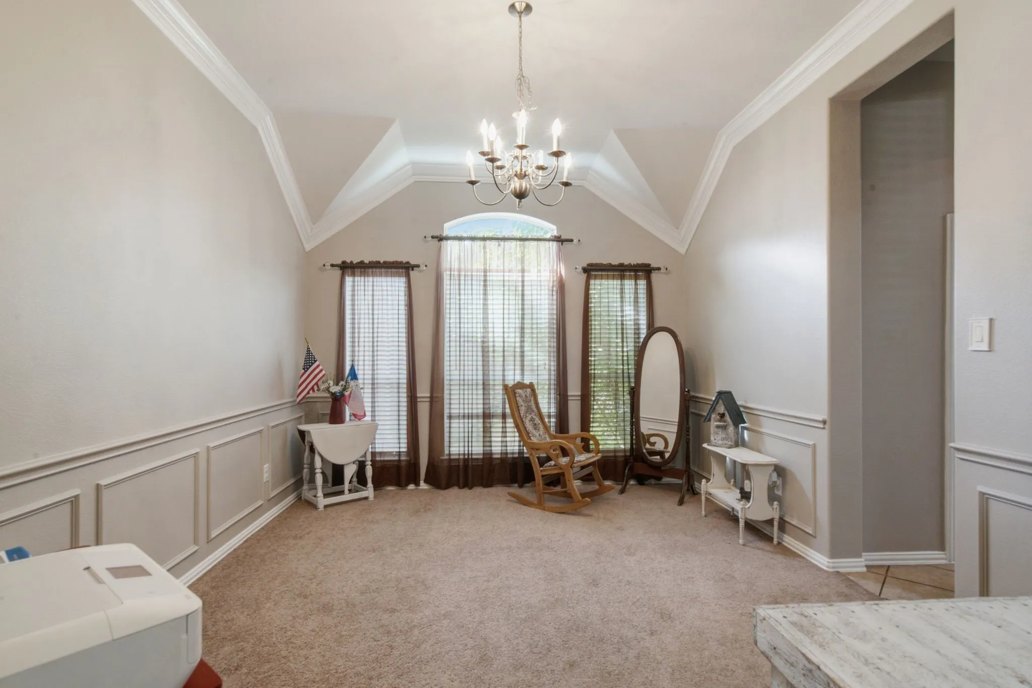 Formal dining room featuring tall windows with horizontal blinds, wainscoting, crown molding, and a chandelier