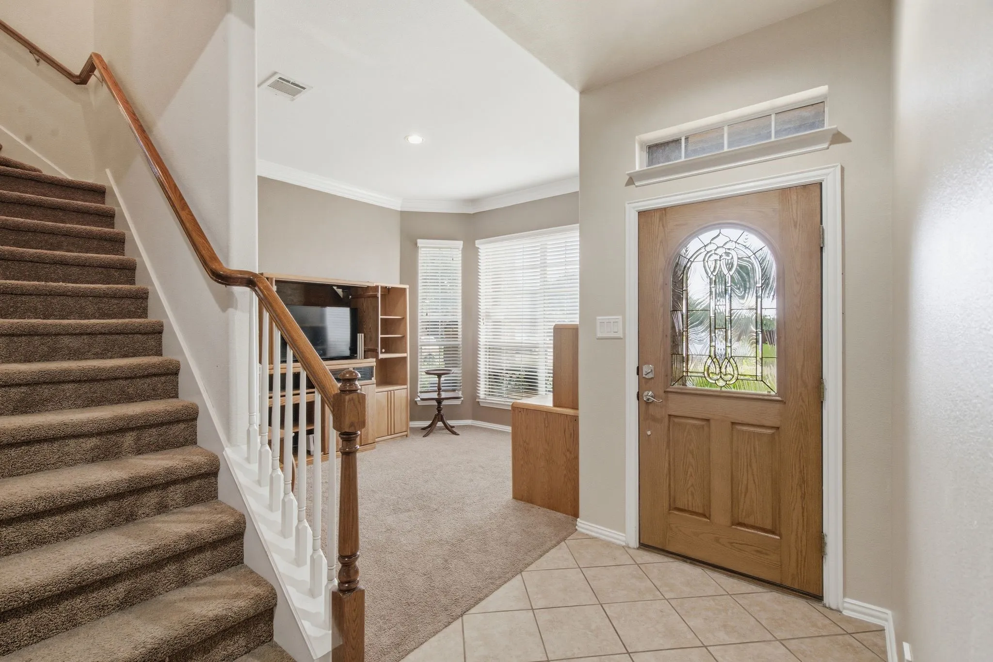 Entryway featuring a wood-panel door with decorative glass, transom window, and tile flooring