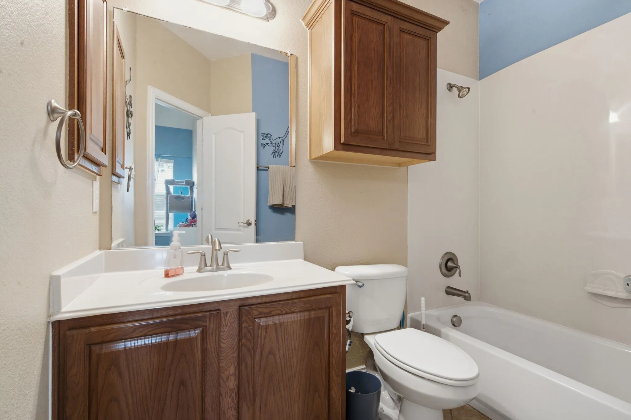 Upstairs bathroom featuring a single vanity with wood-finish cabinetry, a white countertop, and a built-in sink