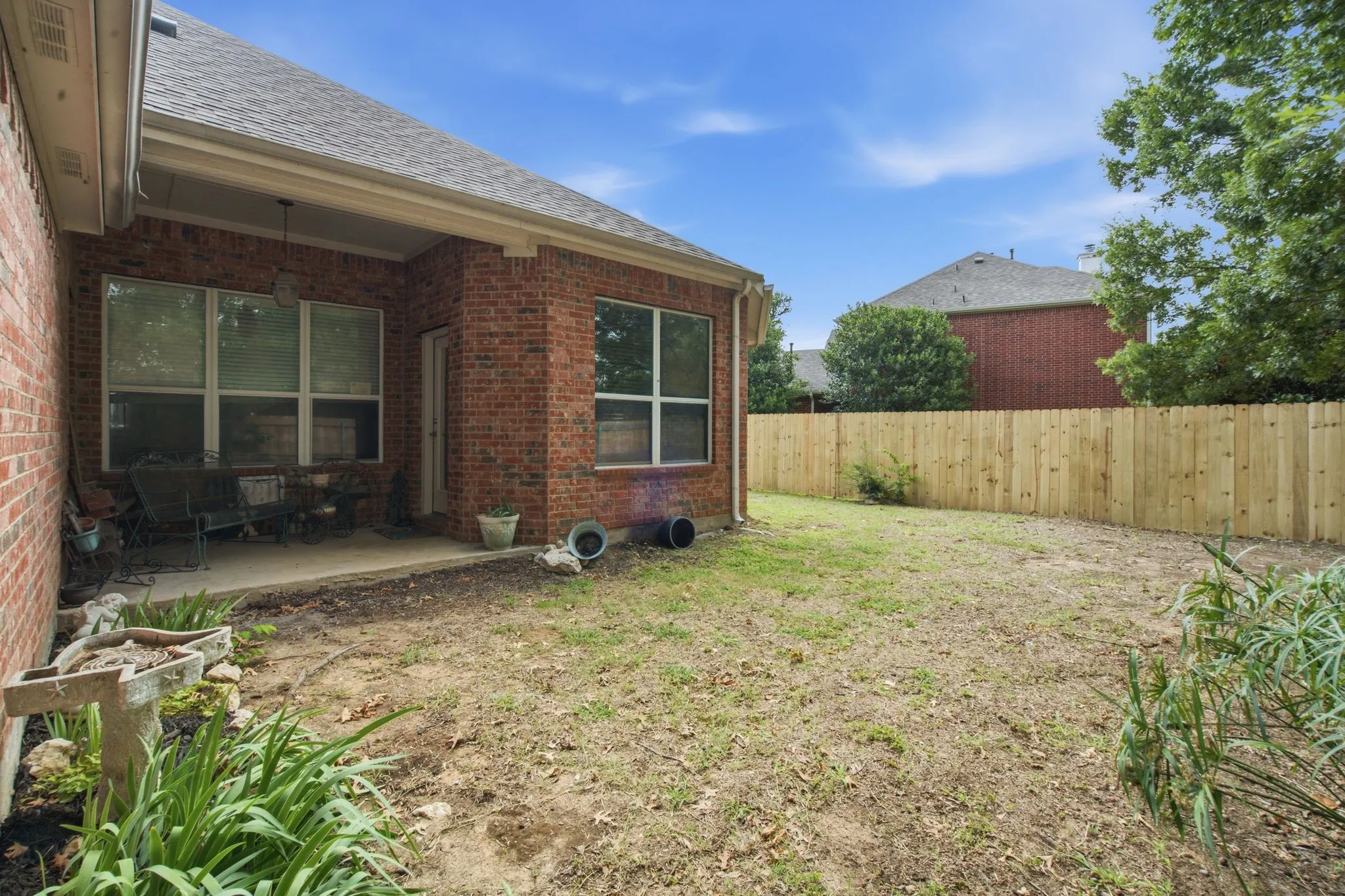 Expansive backyard featuring a new wood privacy fence, a covered patio, and brick exterior