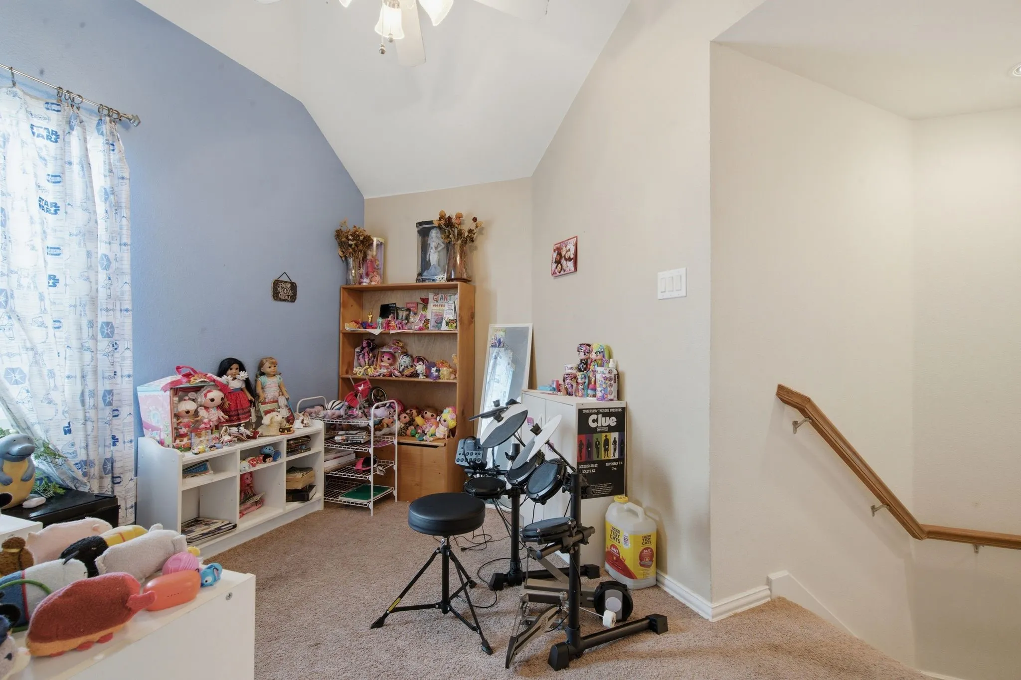 Upstairs loft area  featuring a vaulted ceiling with a ceiling fan, a light blue accent wall, and neutral carpet flooring