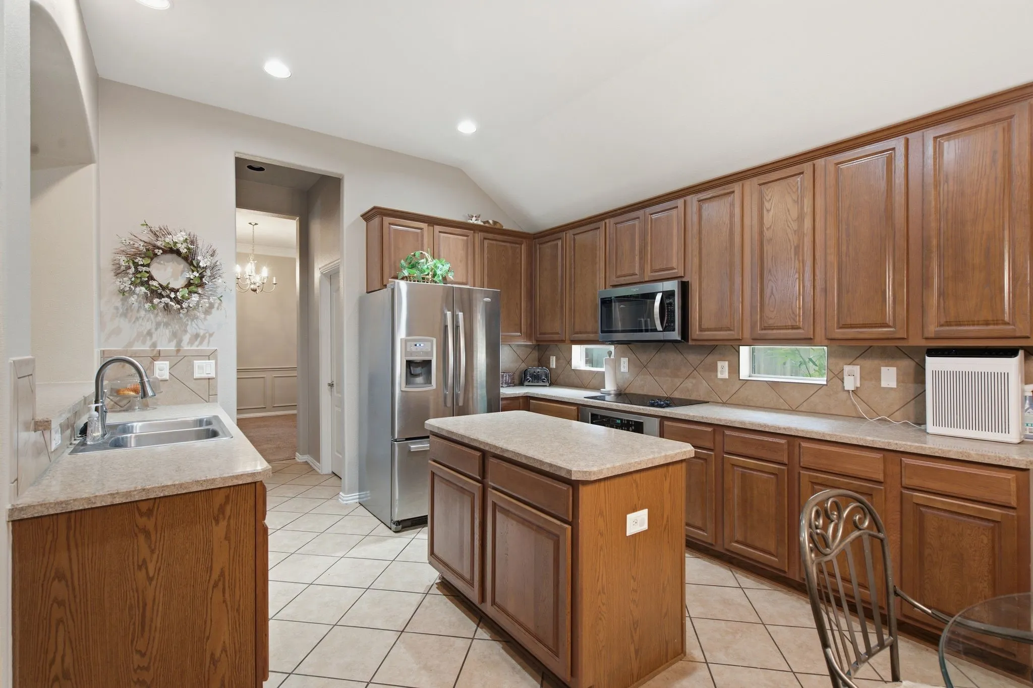 Kitchen featuring wood cabinetry, stainless steel appliances, a center island with countertop, tile flooring, and recessed lighting