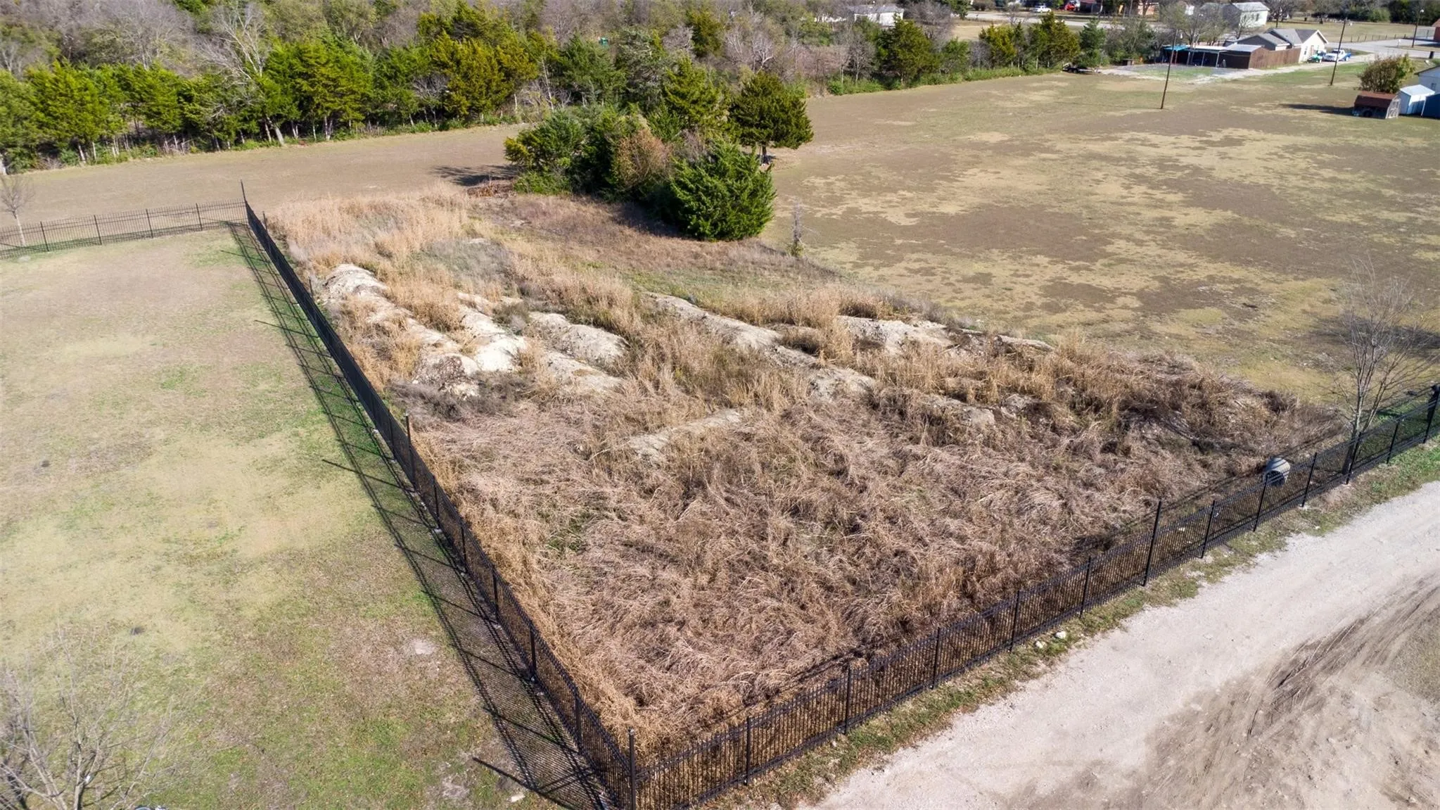Fenced land parcel featuring a perimeter fence and a partially cleared area