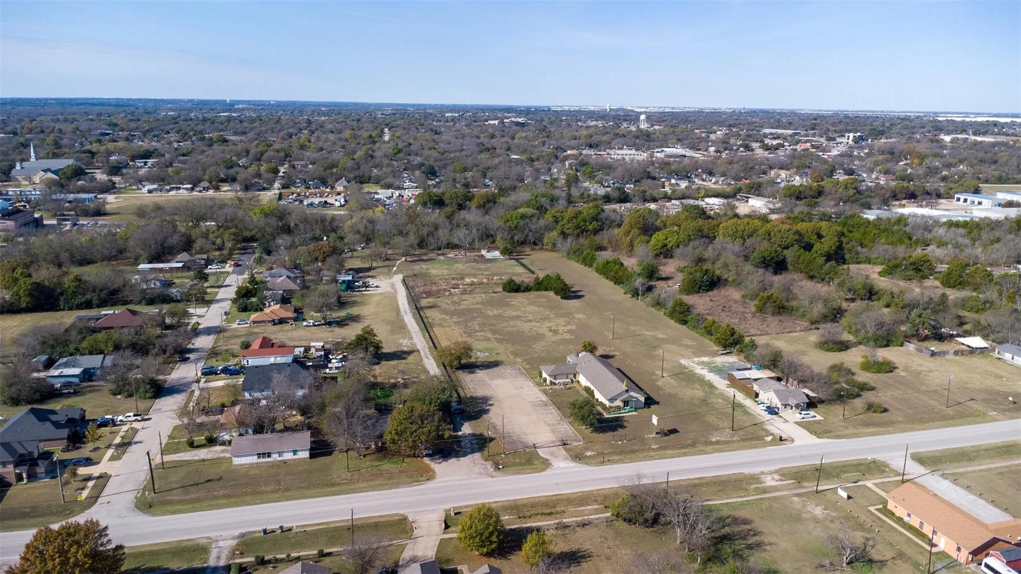 Expansive property featuring undeveloped land with surrounding residences and commercial structures