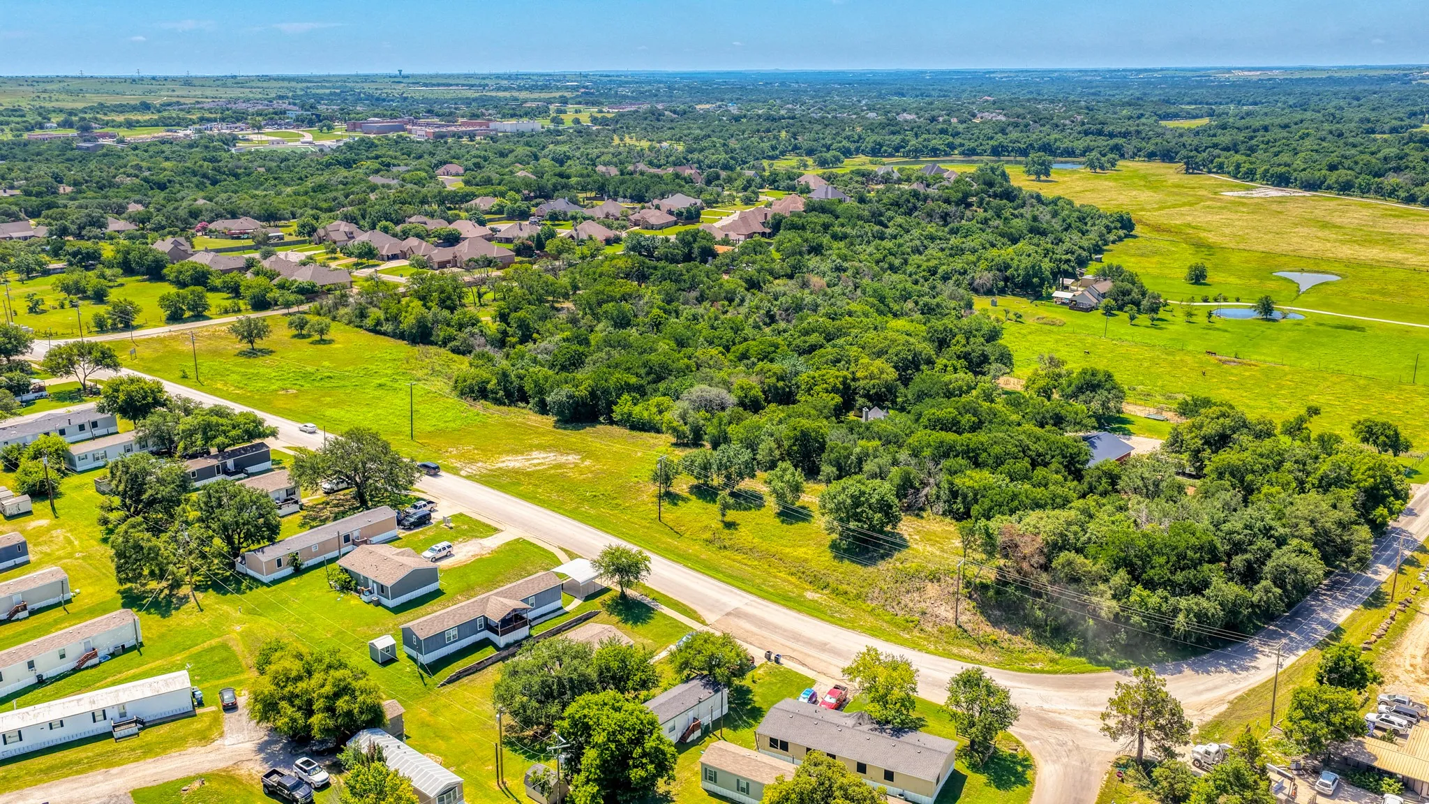 Expansive green spaces and mature trees characterize this aerial landscape