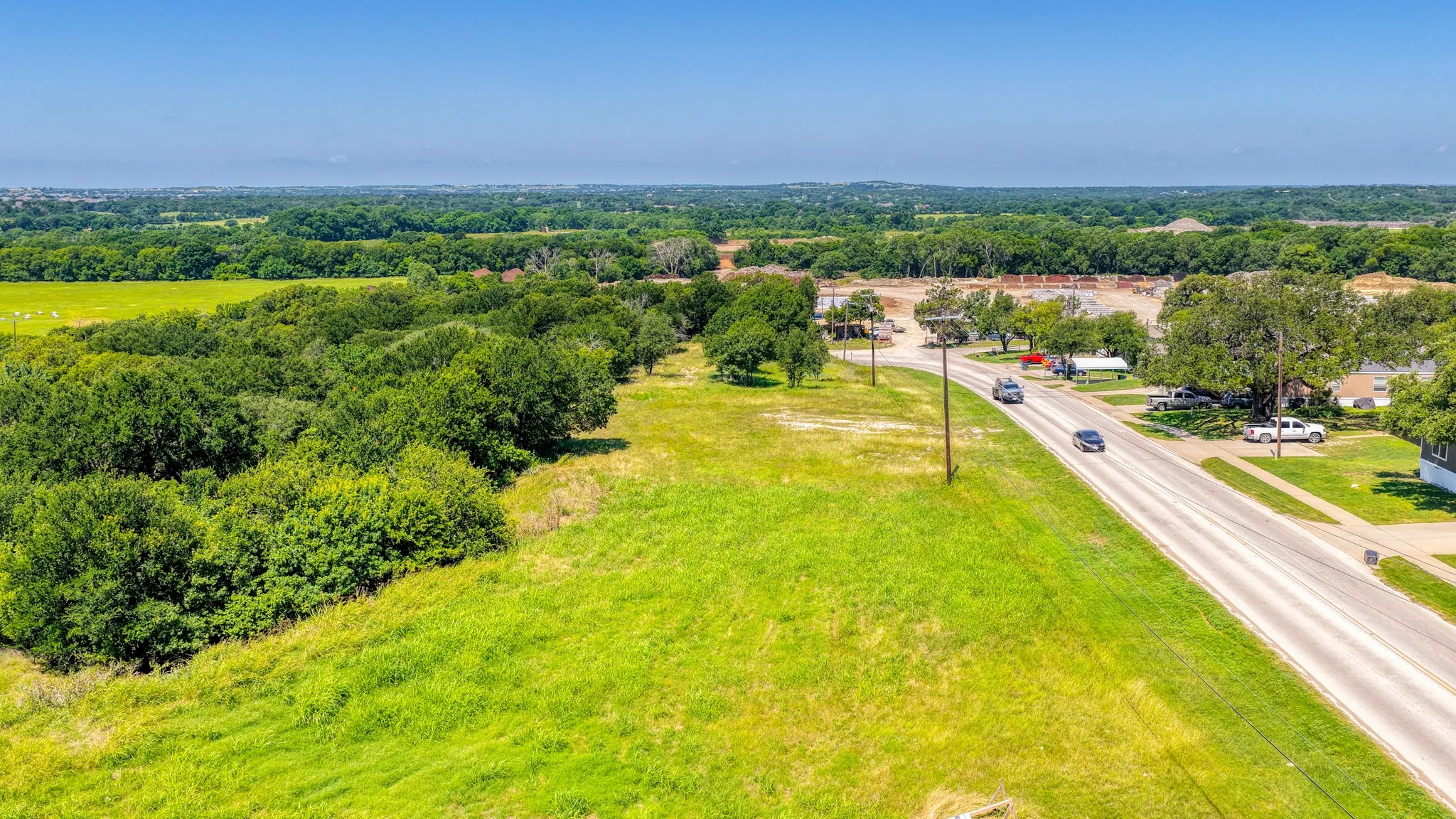 Expansive undeveloped land featuring a cleared grassy area and mature tree lines
