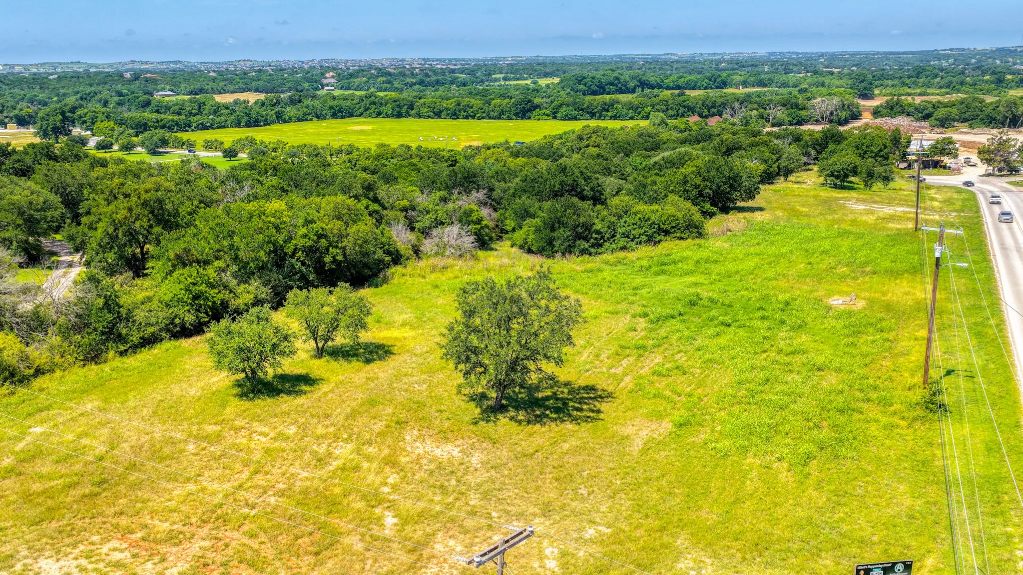 Expansive green landscape featuring mature trees and a clear blue sky