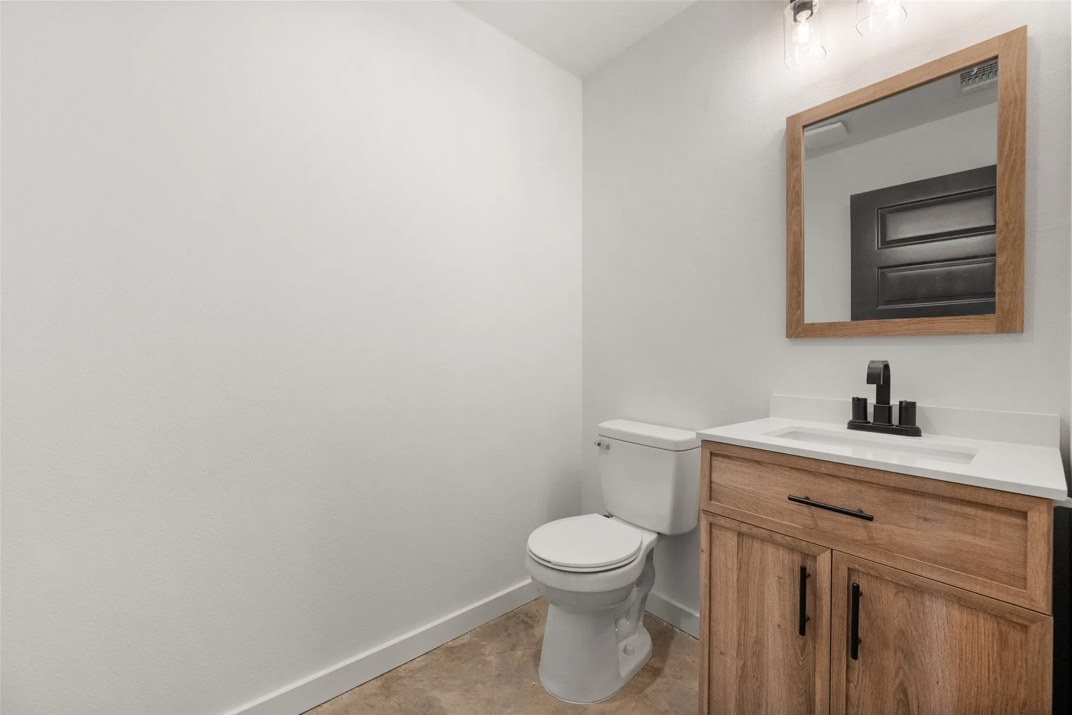 Bathroom vanity featuring a wood-finish cabinet, white countertop, and integrated sink
