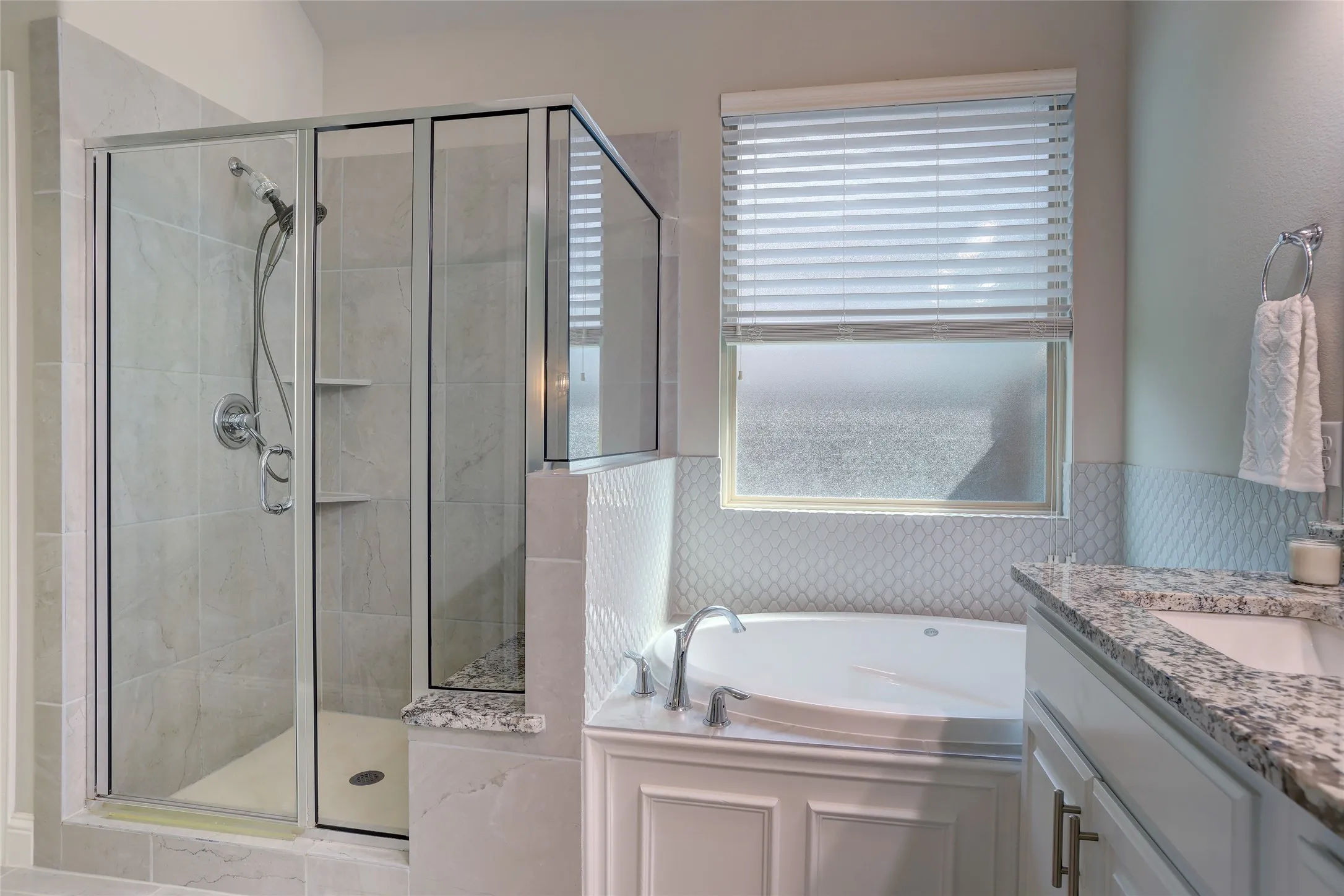 Bathroom featuring a glass-enclosed shower, built-in bathtub, window with blinds, and a vanity with a countertop and undermount sink