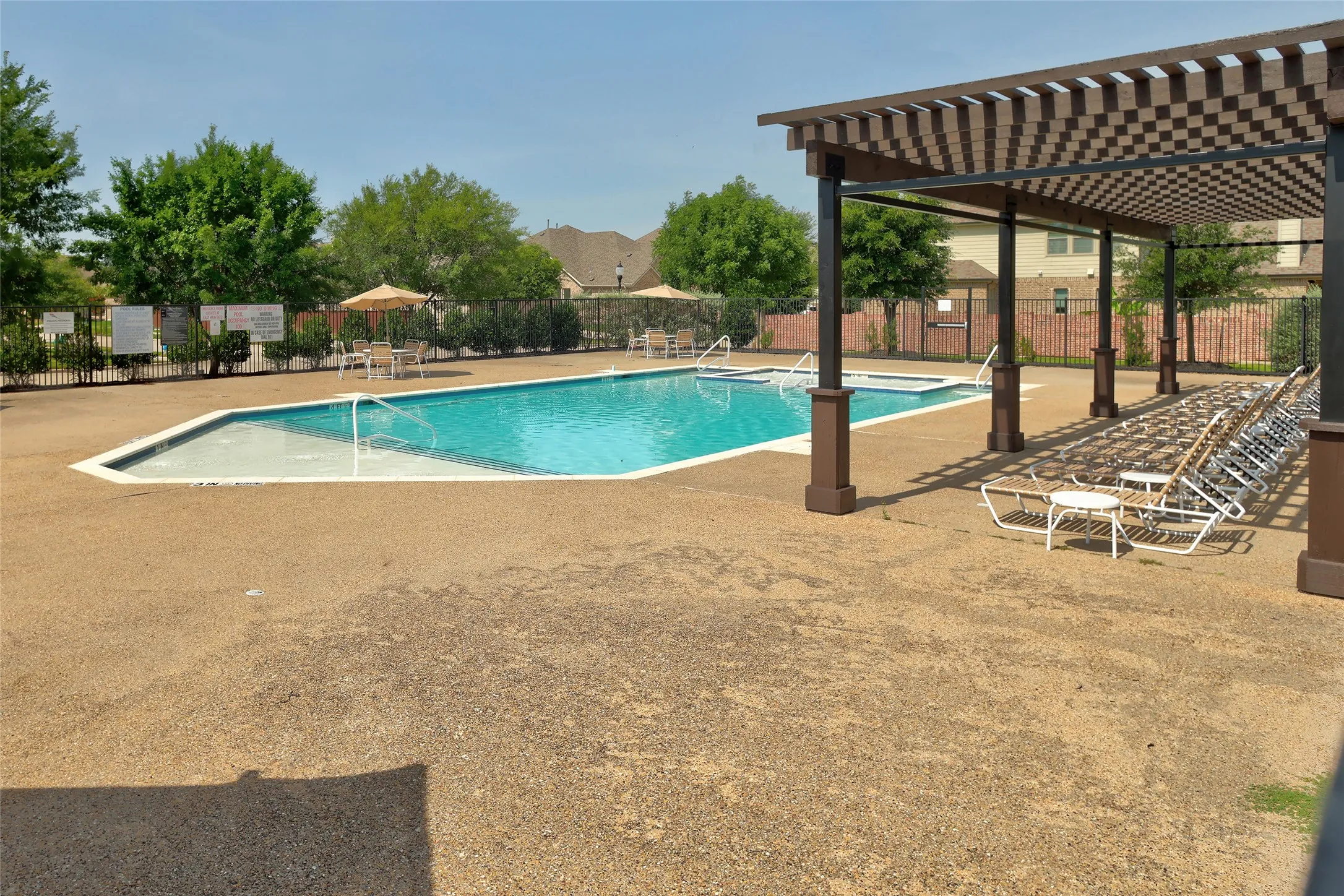 Resort-style pool area featuring a large swimming pool, an integrated spa, and an adjacent shaded pergola