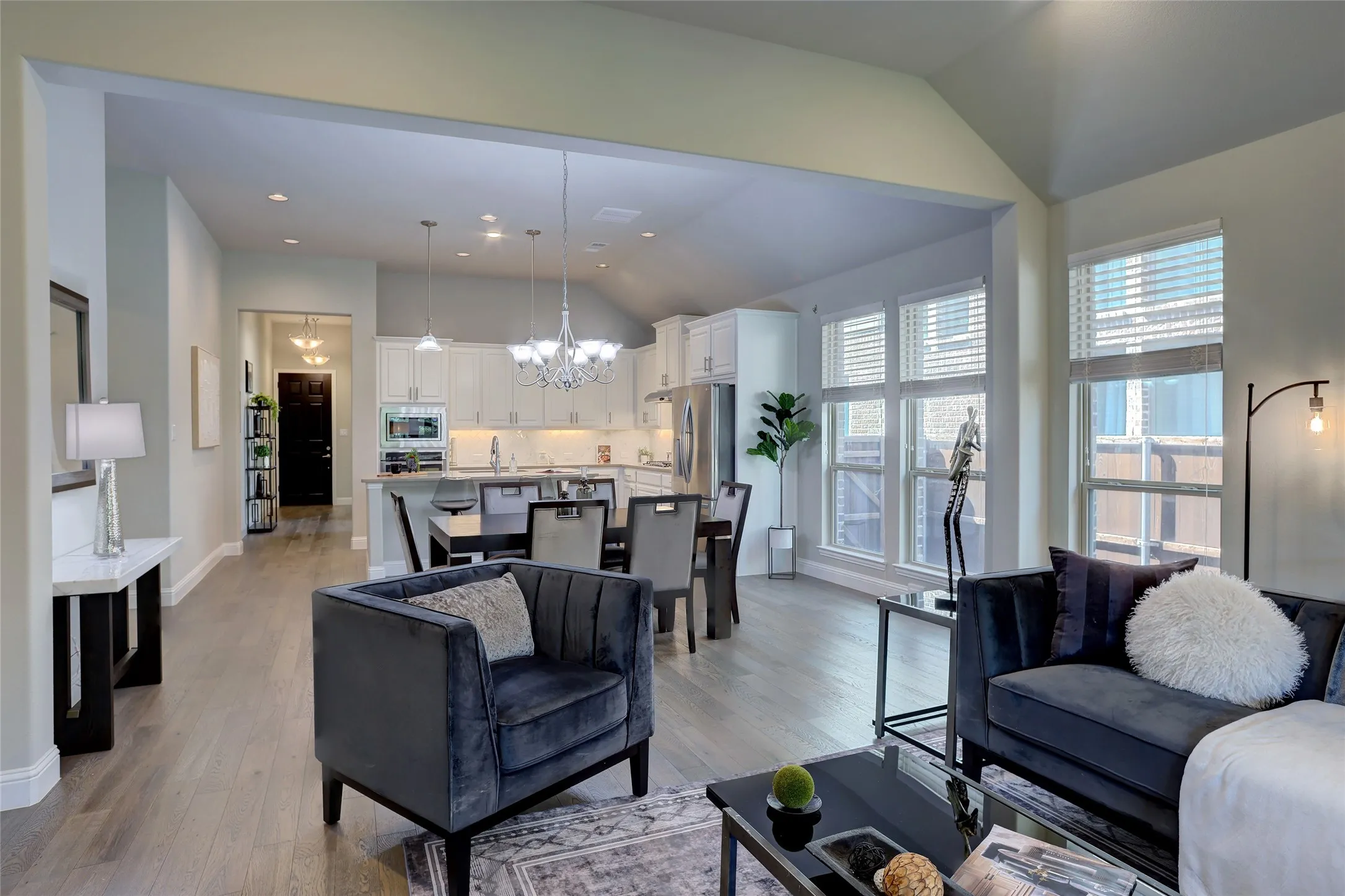 Open-concept living area featuring wood-finish flooring, a vaulted ceiling, and an abundance of natural light from multiple windows