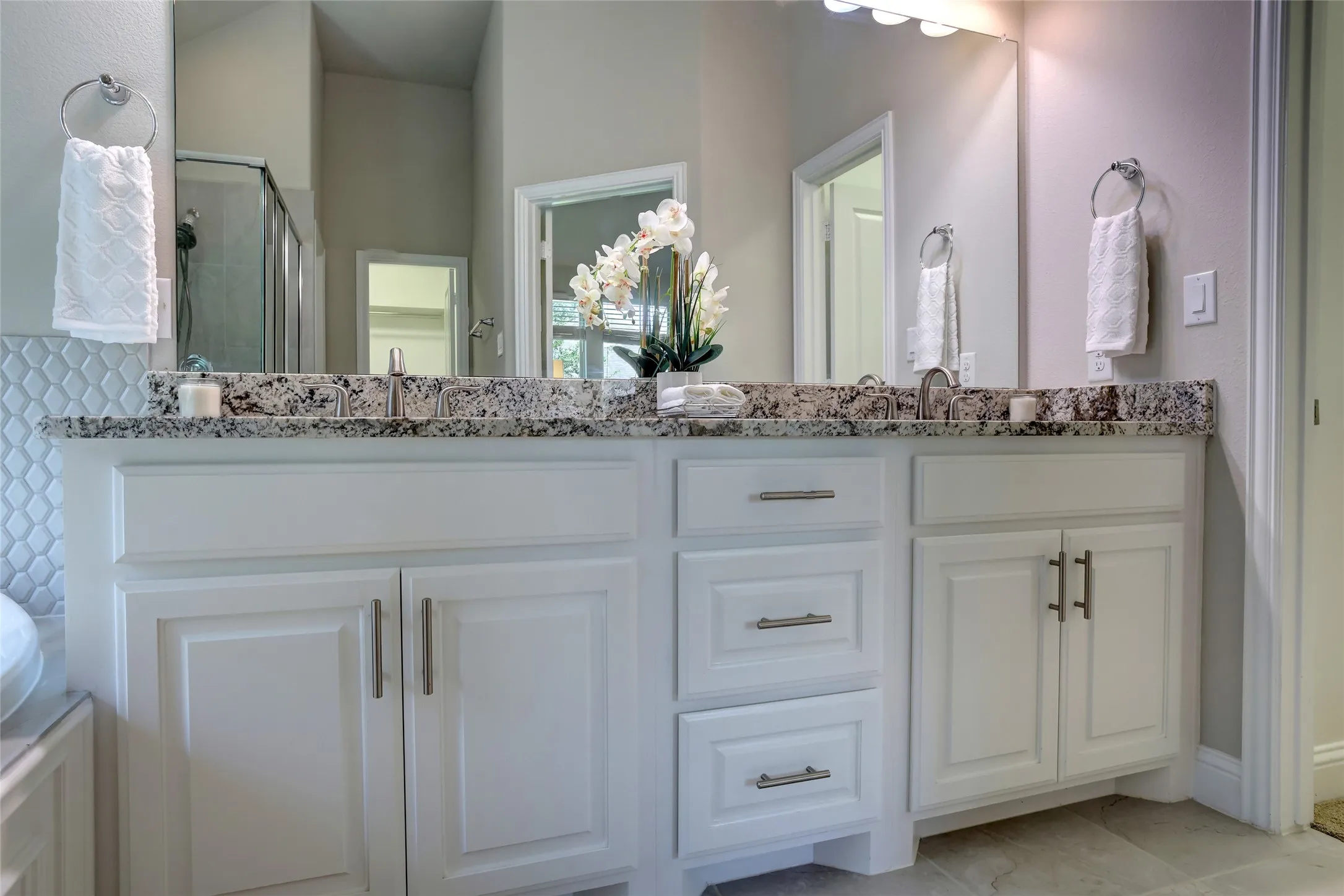 White double vanity with granite countertop, undermount sinks, and brushed nickel hardware
