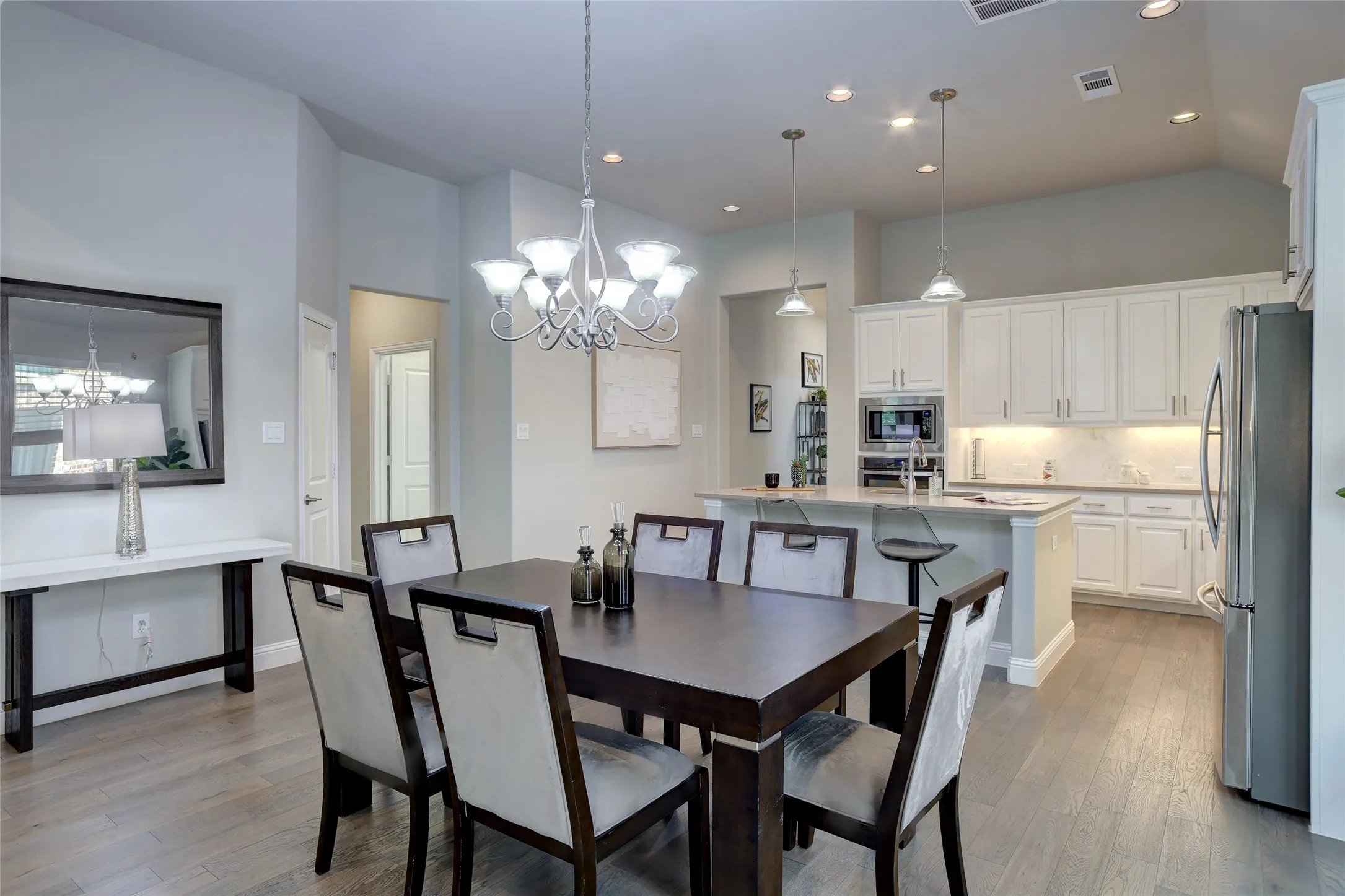 Open-concept dining area with wood-finish flooring, vaulted ceilings, and a chandelier